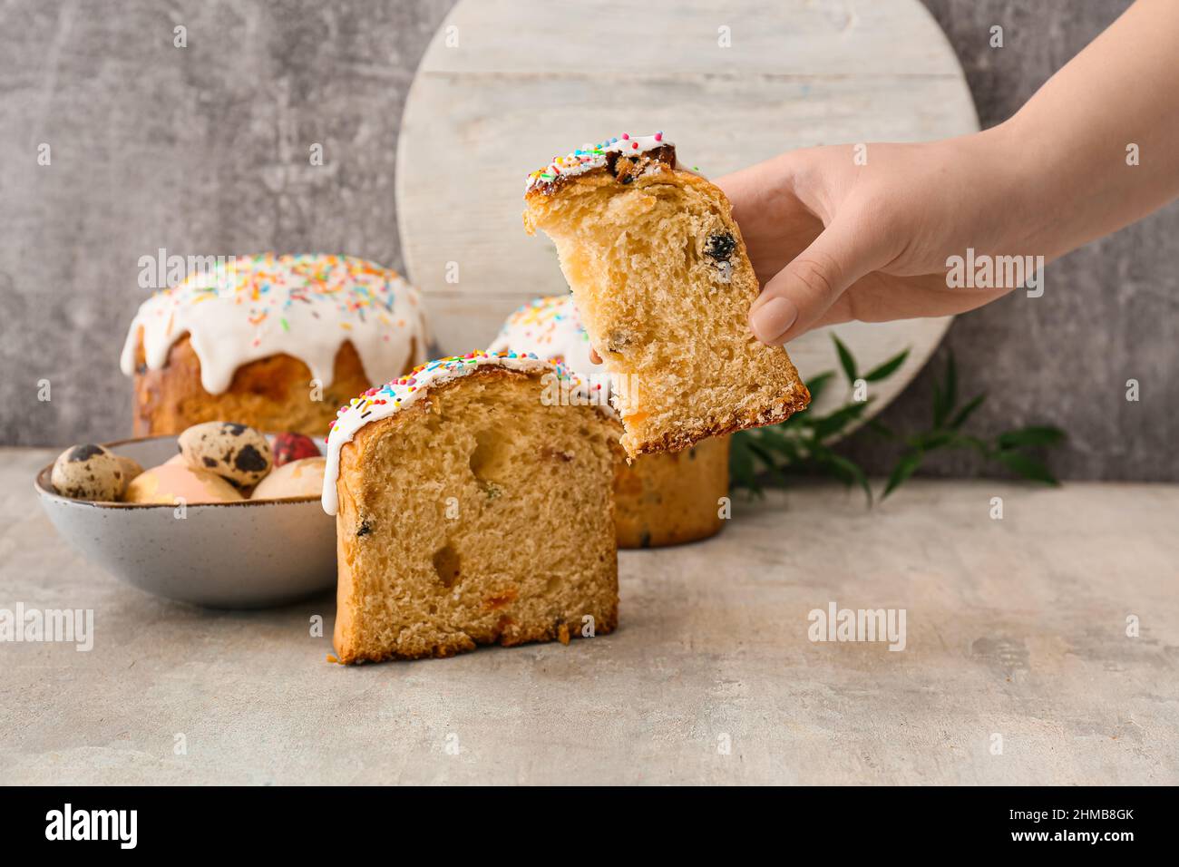 Frau hält ein Stück leckeren Osterkuchen auf grauem Hintergrund Stockfoto
