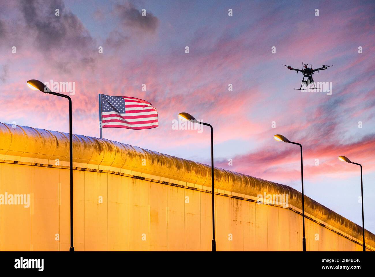 Amerikanische Flagge auf Gefängnis/Grenzmauer mit Drohne am Himmel: Einwanderung, Grenzkontrolle, US-Gefängnisdienst... Konzept Stockfoto