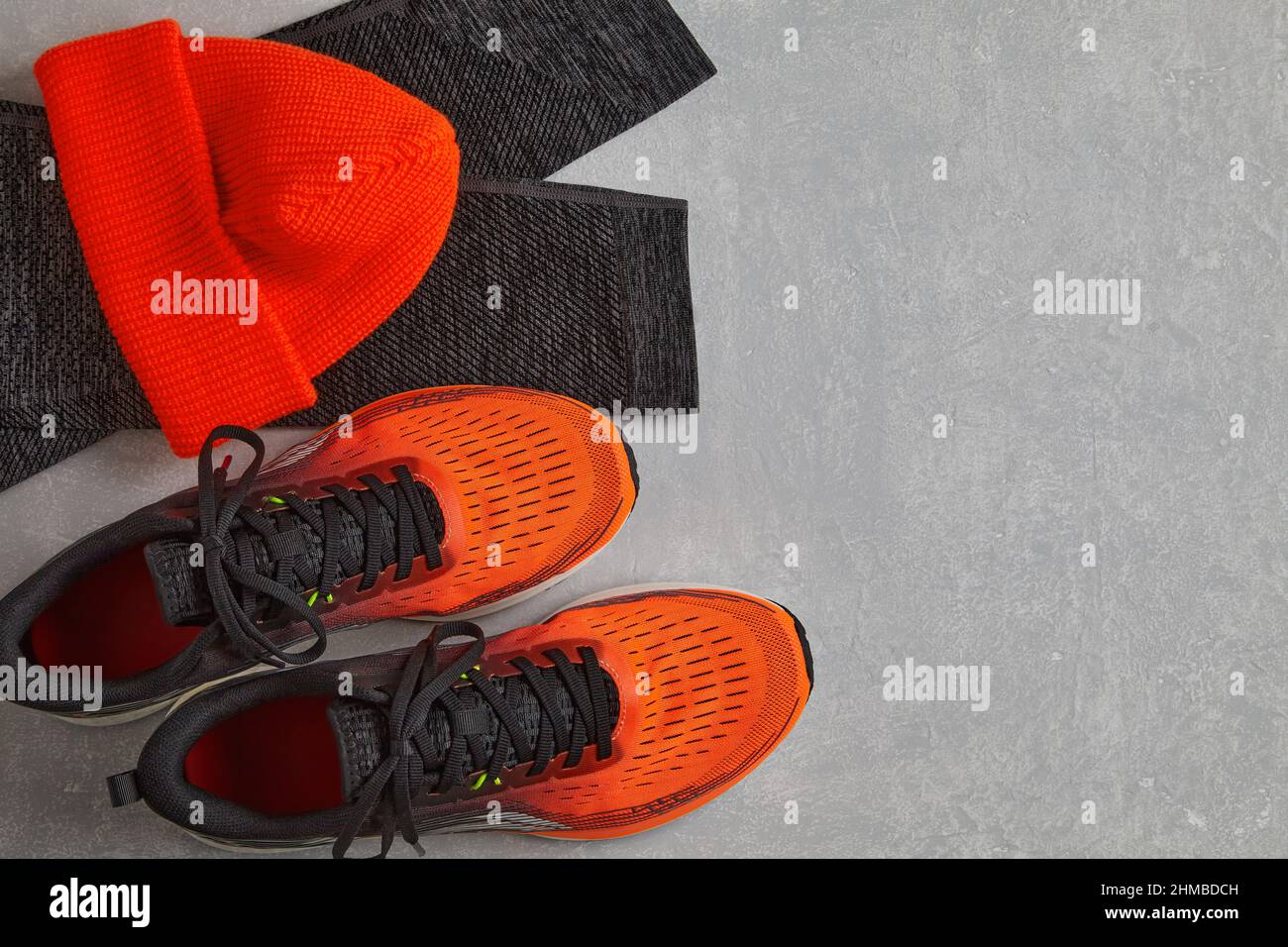 Warme Strickmütze in Orange, warme Sport-Leggings und orangefarbene Laufschuhe Stockfoto
