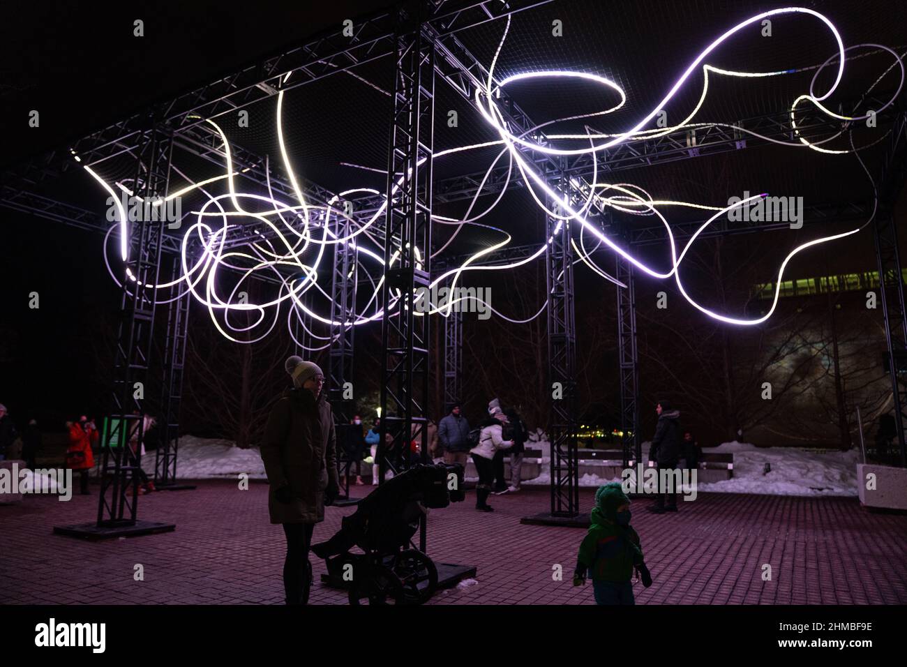 Toronto, Kanada. 07th. Februar 2022. Eine Mutter und ein Kind, die bei einer Außenkunstinstallation ‘Pressure' von Hans E. Madsen und Frederik D. Hougs zu sehen sind, ein Stück, das aus einer 300 Meter langen, pulsierenden RGB-LED-Lichterkette besteht, die einem Doodle ähnelt und um eine große Konstruktion gewickelt ist. Die Nordic Lights Outdoor-Winterausstellung ist eine Ausstellung nordischer und kanadischer Lichtkunst im Toronto Harbourfront Centre, die gemeinsam mit Fjord Studio produziert wurde. Kredit: SOPA Images Limited/Alamy Live Nachrichten Stockfoto