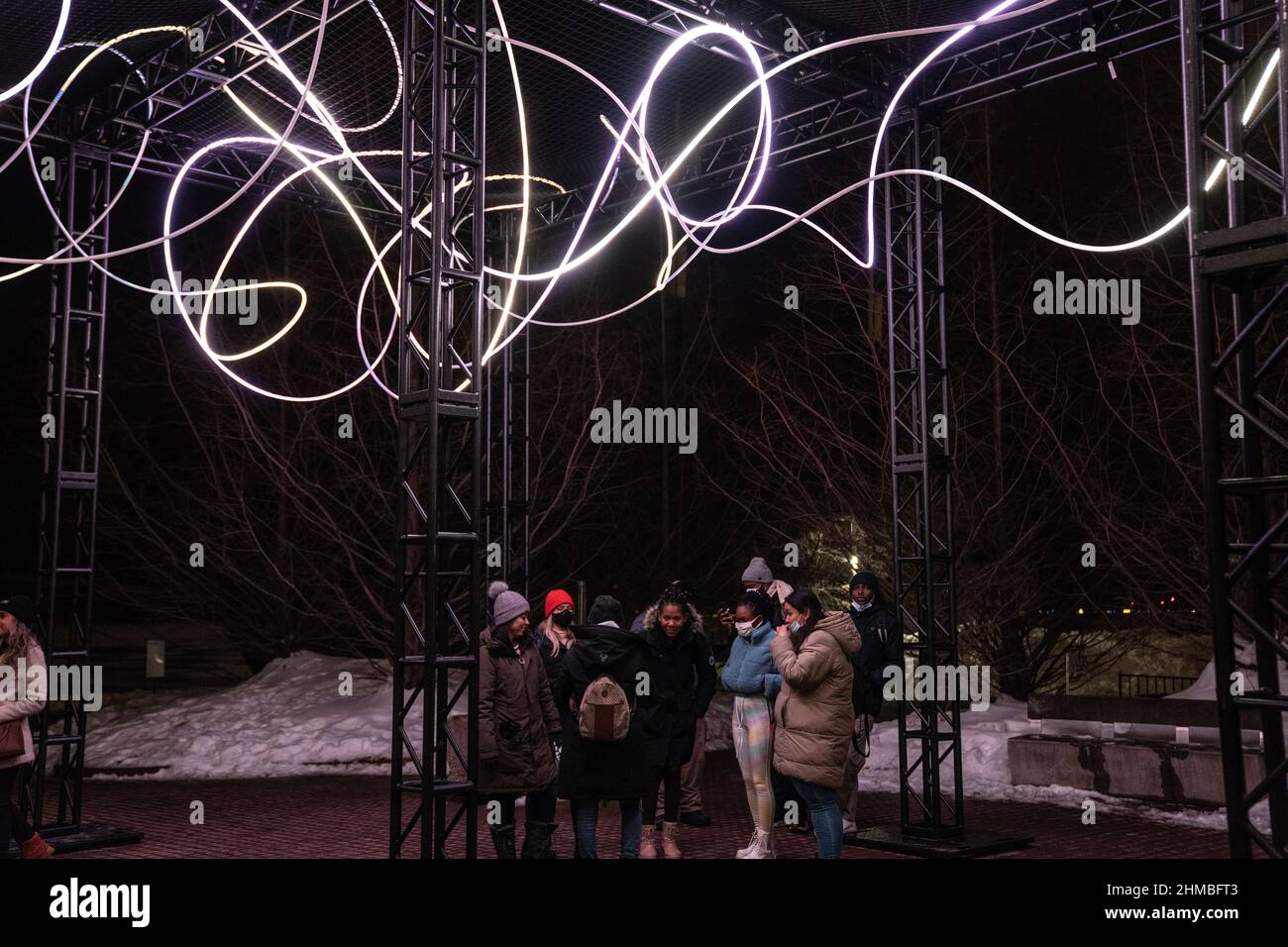 Toronto, Kanada. 07th. Februar 2022. Gemeinsam machen Menschen bei einer Außenkunstinstallation ‘Pressure' von Hans E. Madsen und Frederik D. Hougs ein Gruppenbild, ein Stück, das aus einer 300 Meter langen Kette pulsierender RGB-LED-Leuchten besteht, die einem Doodle ähneln und um eine große Konstruktion gewickelt sind. Die Nordic Lights Outdoor-Winterausstellung ist eine Ausstellung nordischer und kanadischer Lichtkunst im Toronto Harbourfront Centre, die gemeinsam mit Fjord Studio produziert wurde. (Foto von Katherine Cheng/SOPA Images/Sipa USA) Quelle: SIPA USA/Alamy Live News Stockfoto