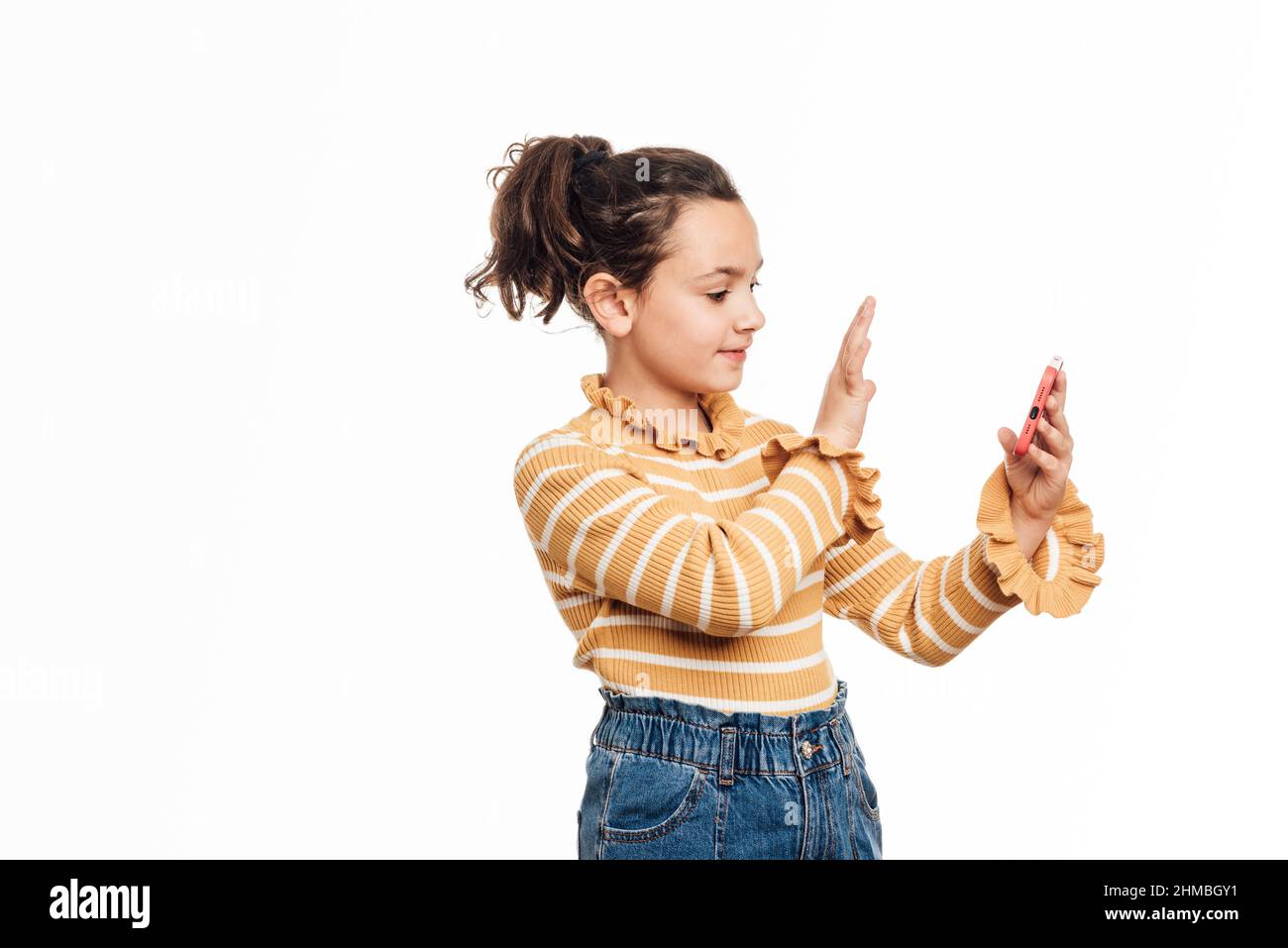Mädchen winkt mit der Hand und grüßt jemanden, während sie ein Video aufnimmt oder einen Videoanruf auf ihrem Mobiltelefon führt. Stockfoto