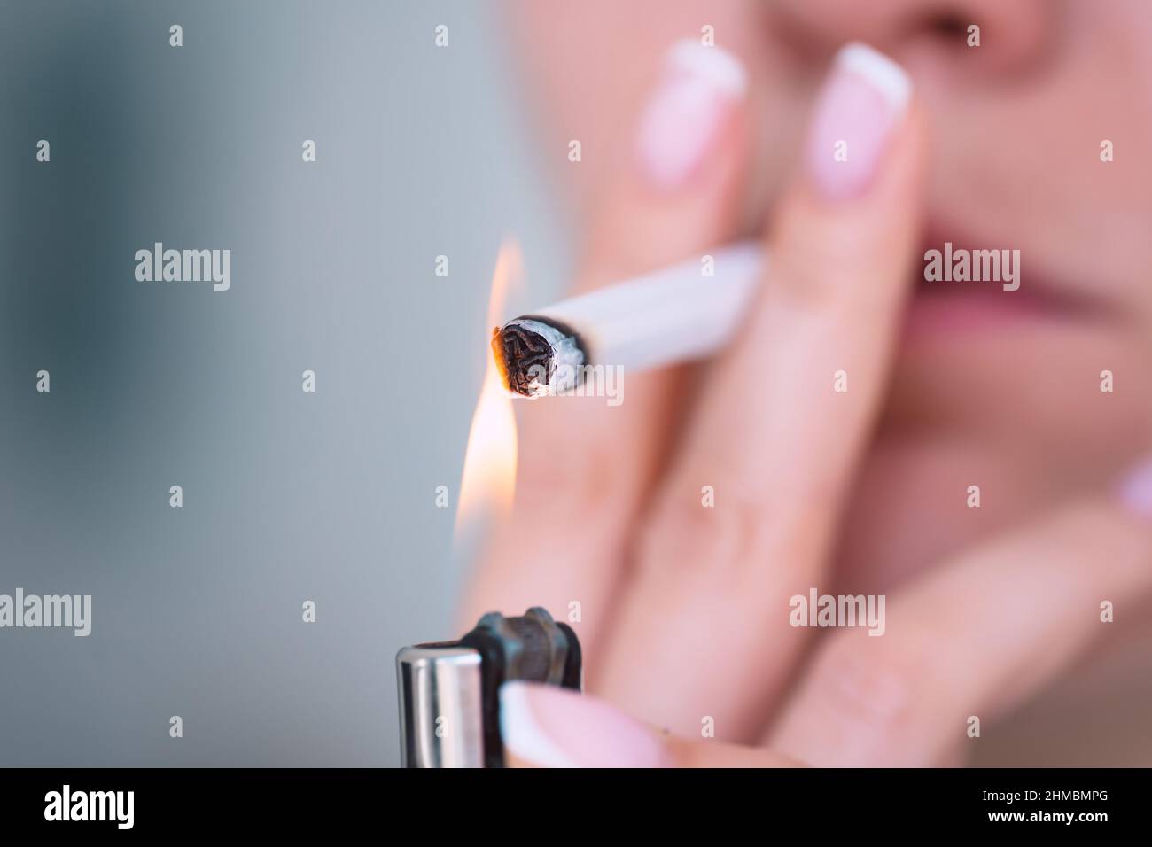 Nahaufnahme einer jungen Frau, die eine Zigarette mit Feuerzeug anzündet. Rauchen sucht und schlechte Gewohnheit Konzept Stockfoto
