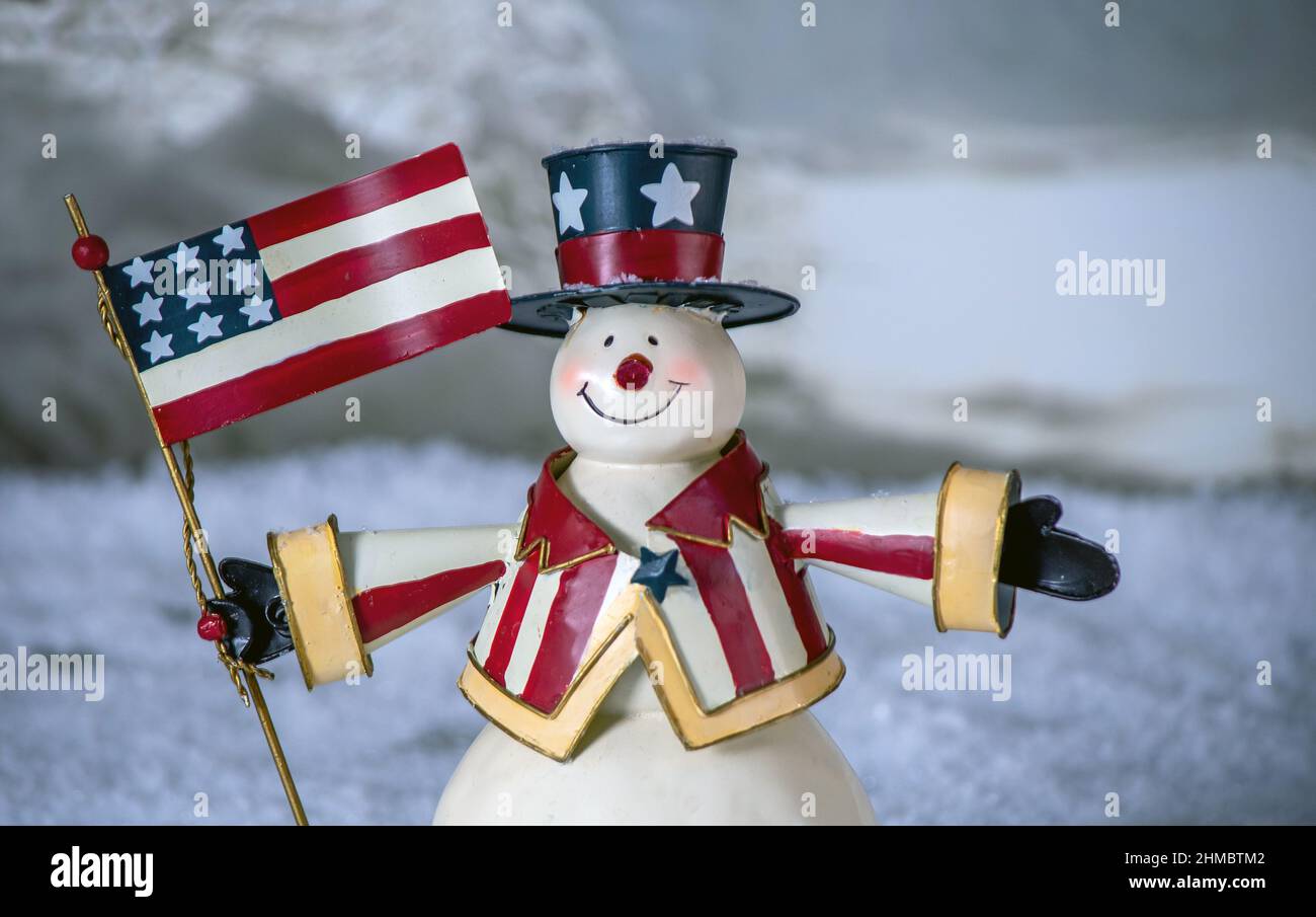 Ein patriotischer Schneemann hält eine amerikanische Flagge und trägt eine sehr amerikanische Weste und einen Zylinderhut Stockfoto