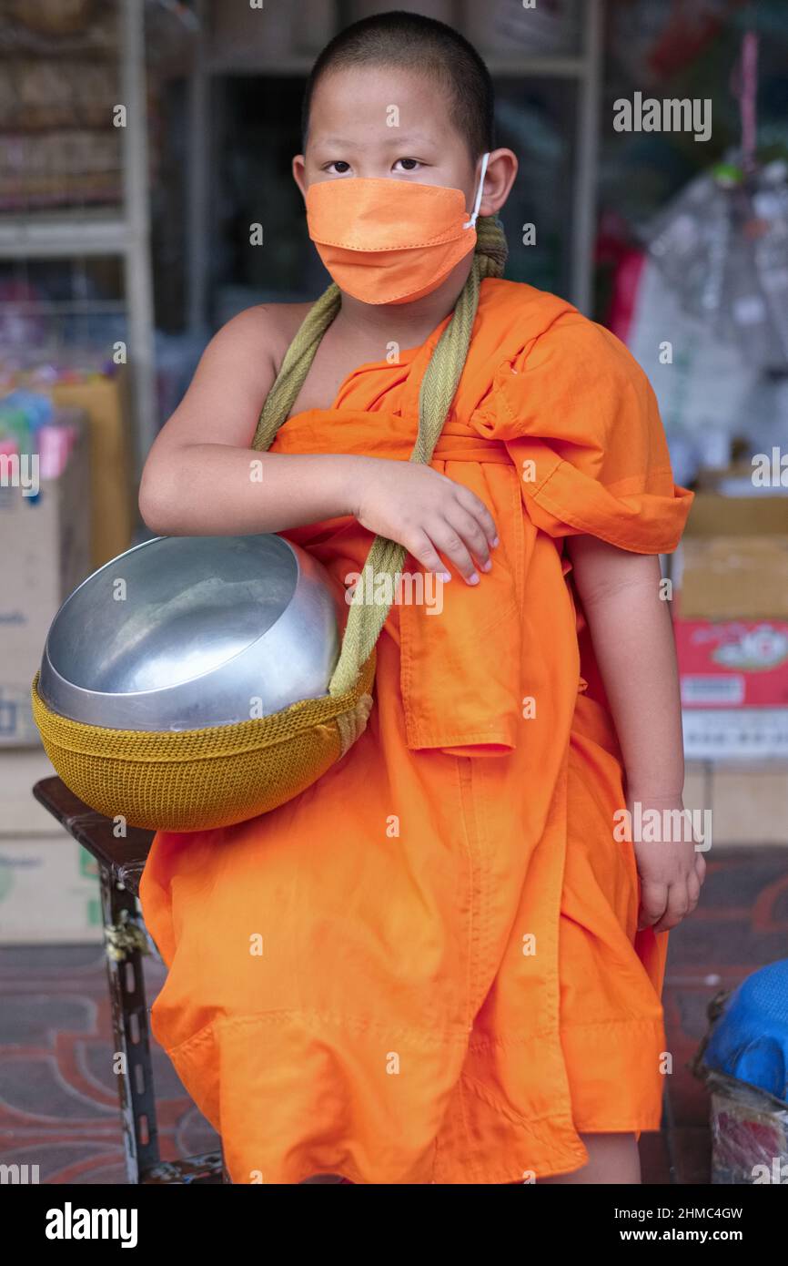 Ein junger, 8 Jahre alter buddhistischer Kindermönch oder Novize während der traditionellen Morgenalmosenrunde, wobei die Almosenschale getragen wird; Bangkok, Thailand Stockfoto