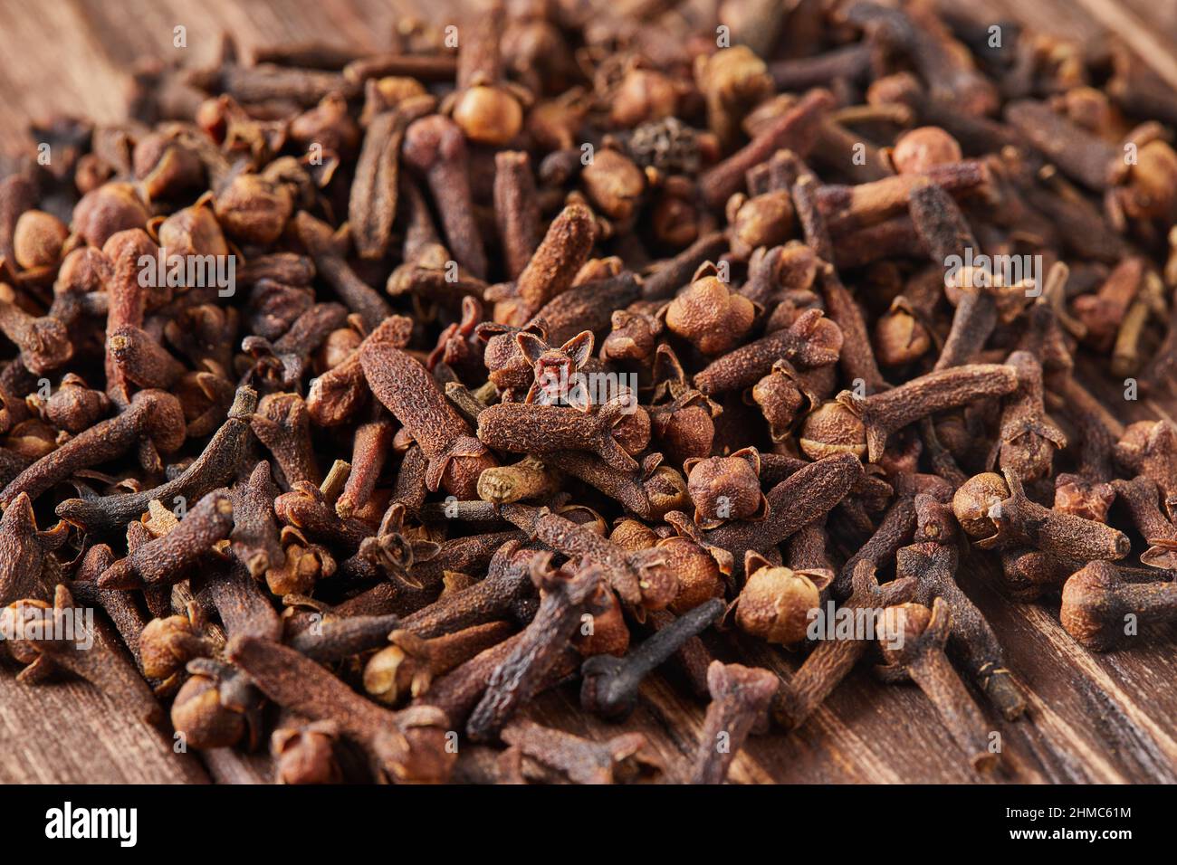 Getrocknete Gewürzkräuter Nelken zum Aromatisieren von Lebensmitteln und natürlichen Medikamenten, indische Gewürzzutat auf Holzhintergrund. Stockfoto