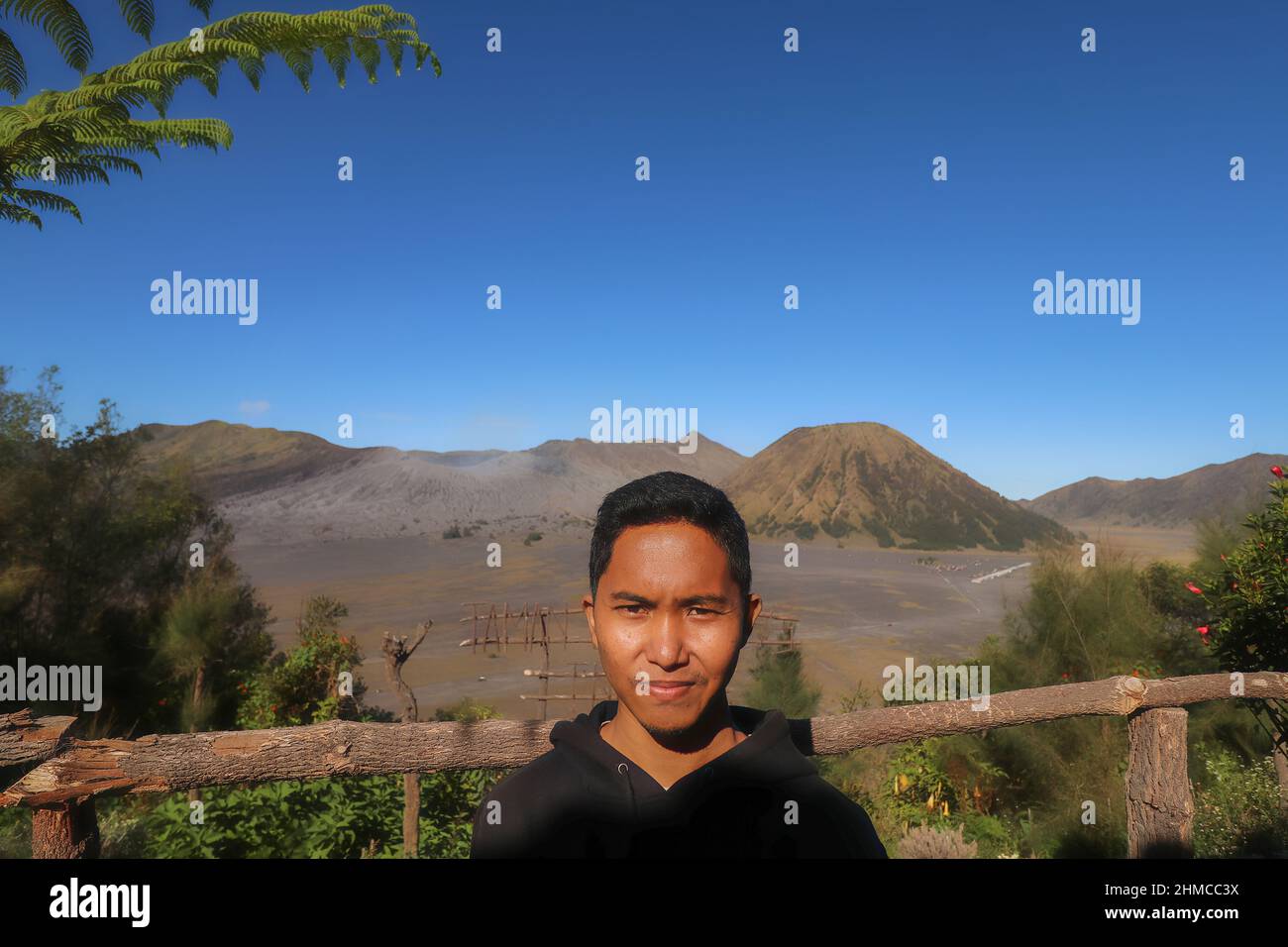 Asiatische Männer posieren auf dem Berg Bromo vor einem hellen blauen Himmel Hintergrund Stockfoto