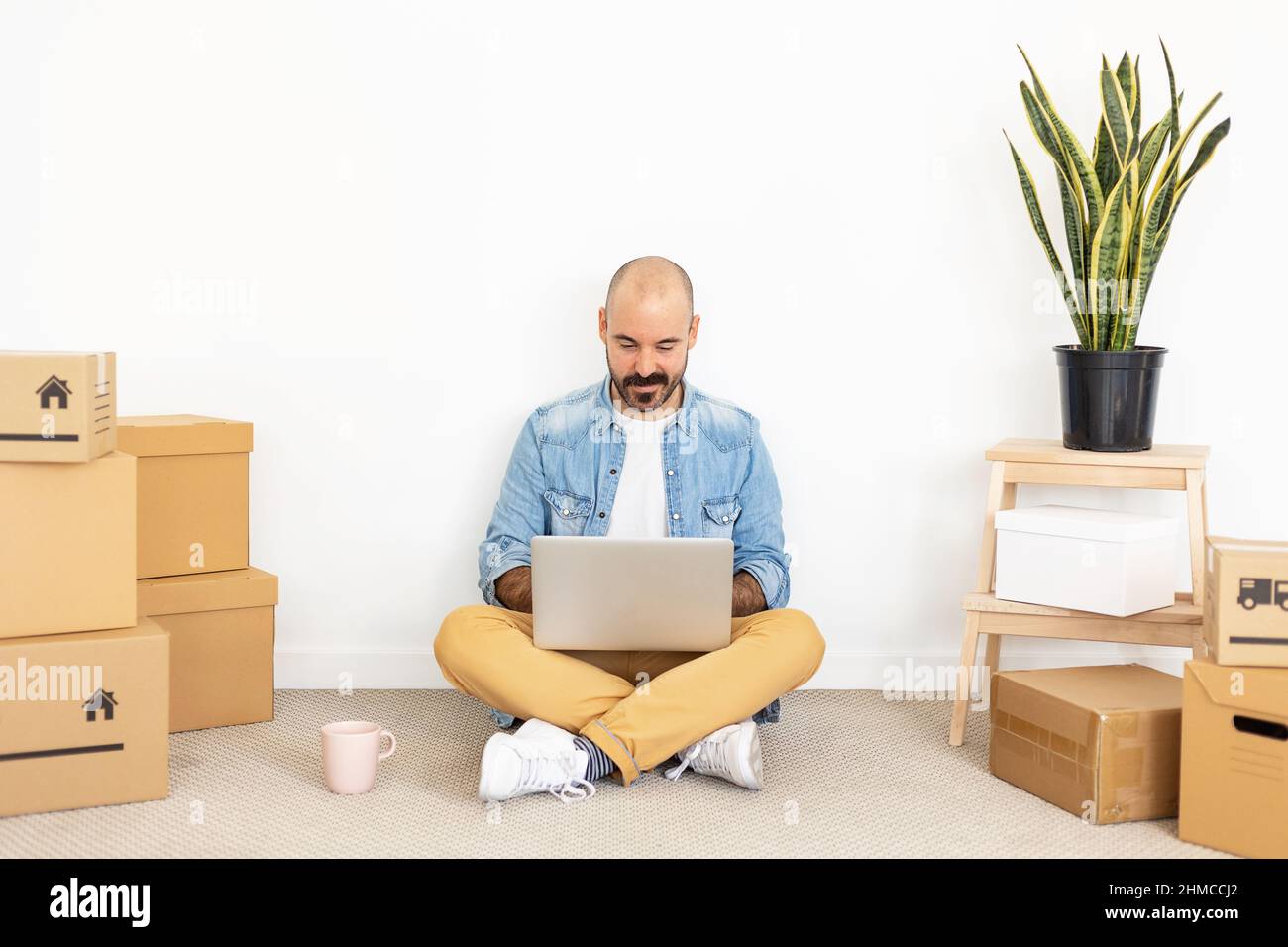 Hipster junger erwachsener Mann mit Laptop in neuem Zuhause Stockfoto