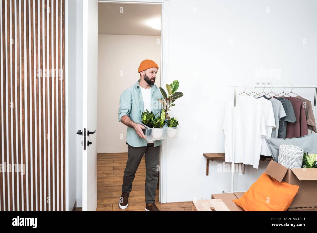 Erwachsener Mann, der am Umzugstag mit Box in ein neues Zuhause geht. Stockfoto