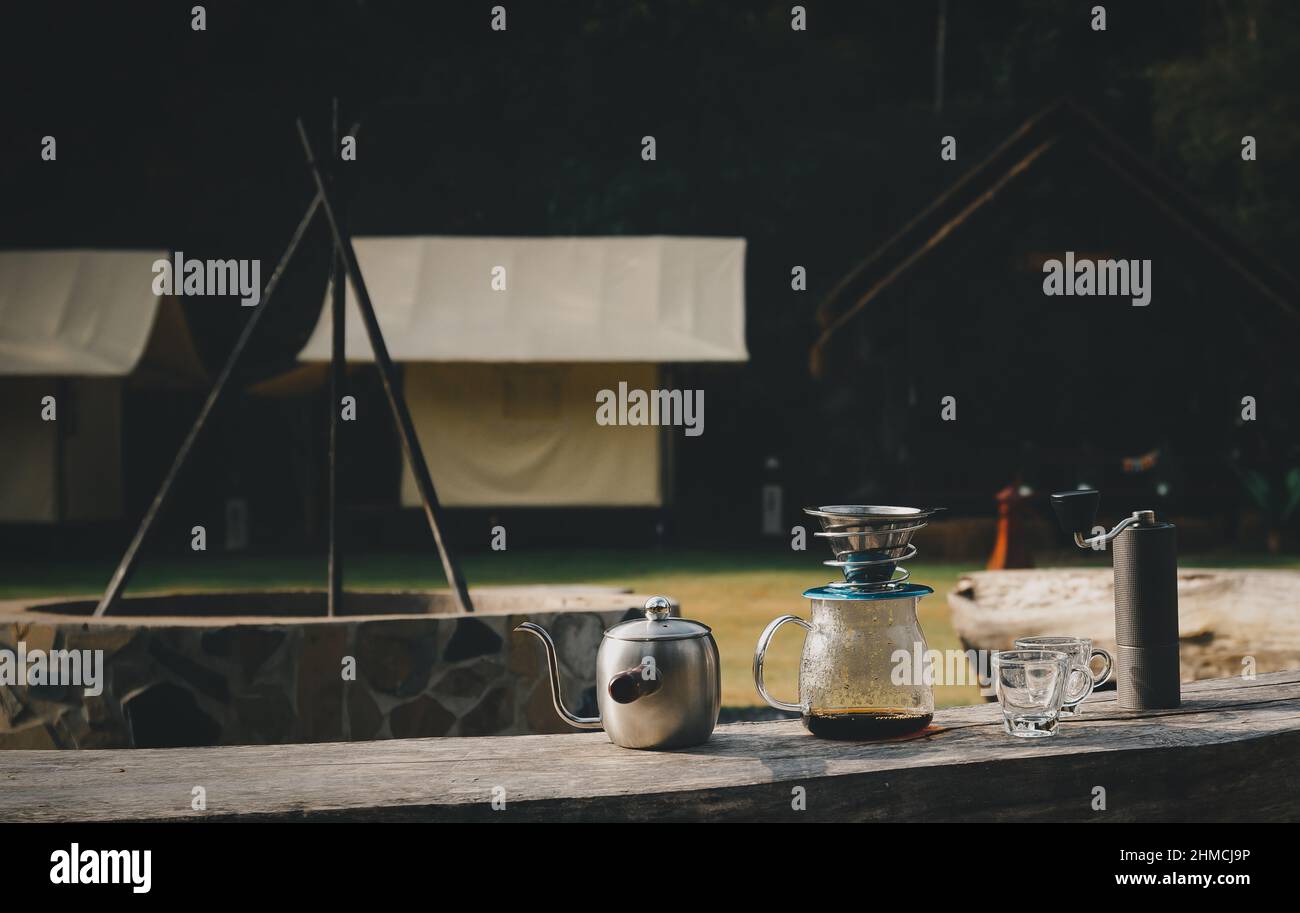 Die Kaffeemaschine befindet sich auf einem Holzstuhl im Campingbereich. Stockfoto
