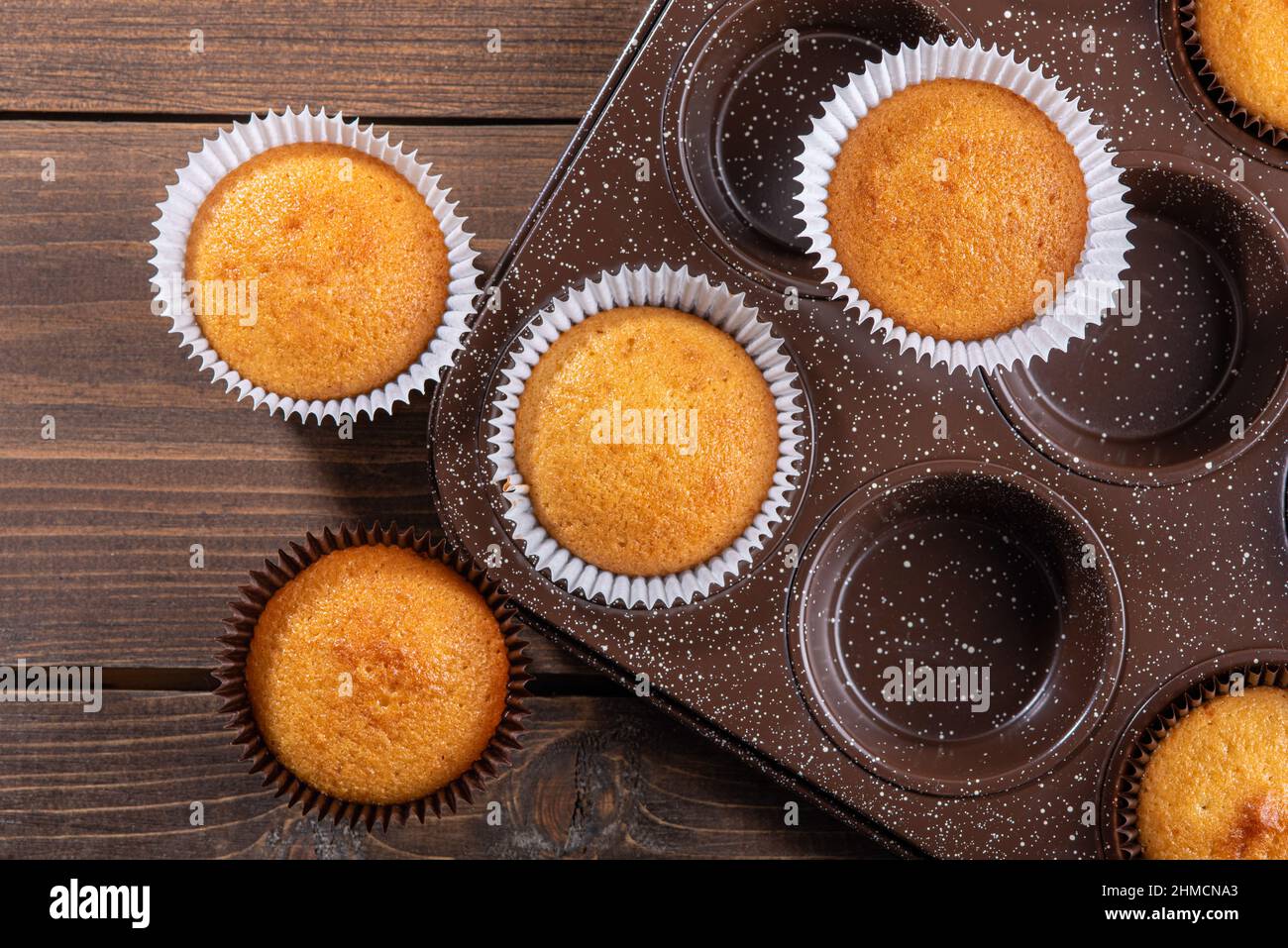 Draufsicht hausgemachte Cupcakes mit Backformen auf Holzhintergrund, hausgemachtes süßes Gebäck Stockfoto