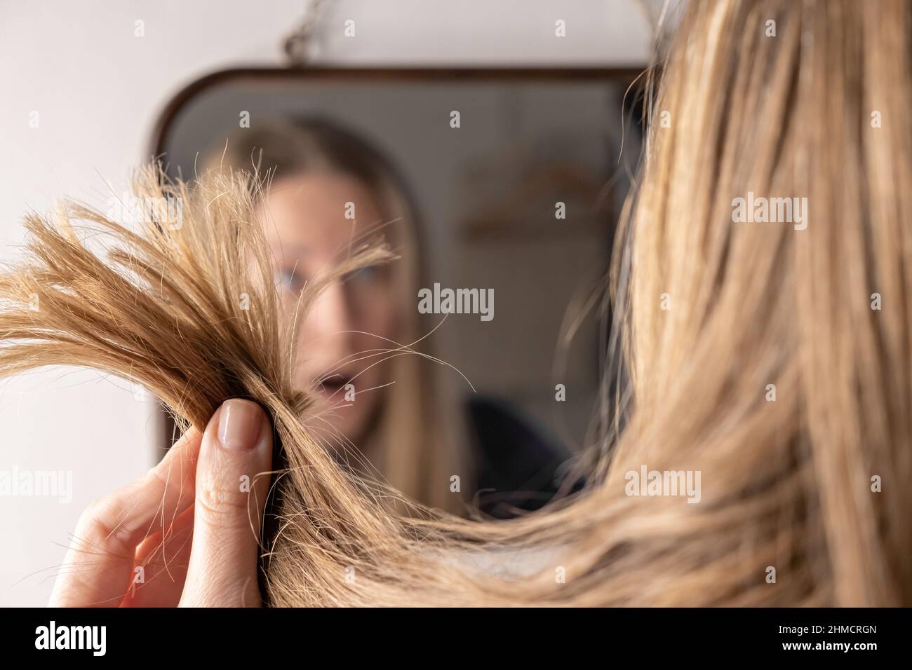 Junge Frau vor dem Spiegel traurig aufgeregt mit Haarausfall Schaden Problem Stockfoto