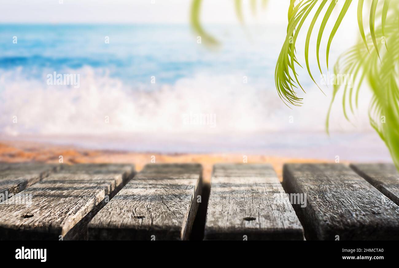 Hintergrund für den Urlaub. Holzlatte mit Palmenblättern am Strand Stockfoto