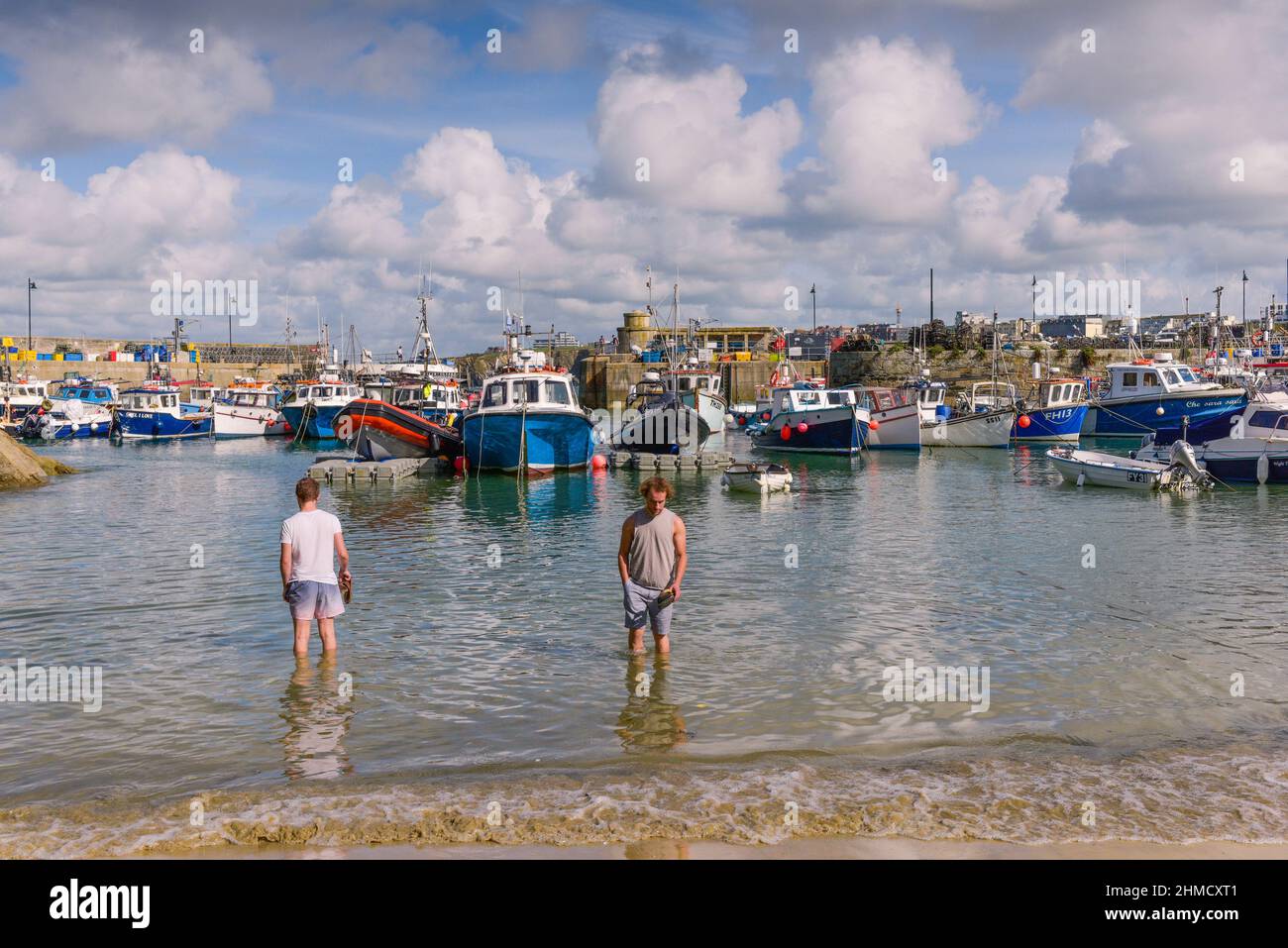 Zwei Männer stehen im Meer am historischen, malerischen Newquay Harbour in Newquay in Cornwall. Stockfoto