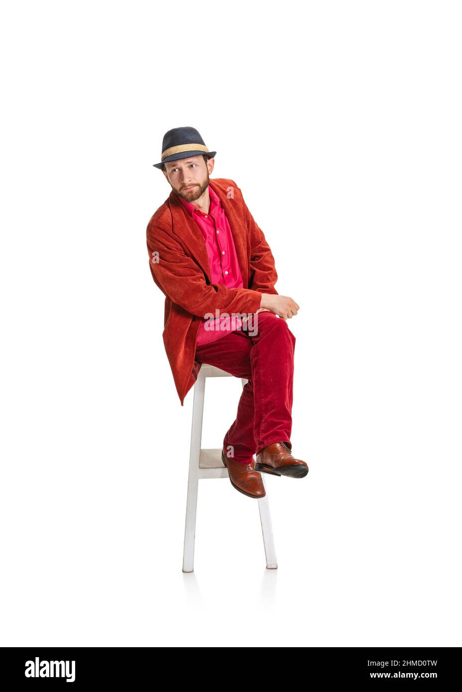 Hübscher junger Mann, Hipster oder Dandy, 50s gekleidet, im Stil von 60s auf einem isolierten Hochstuhl auf weißem Hintergrund sitzend. Retro-Vintage-Style Stockfoto