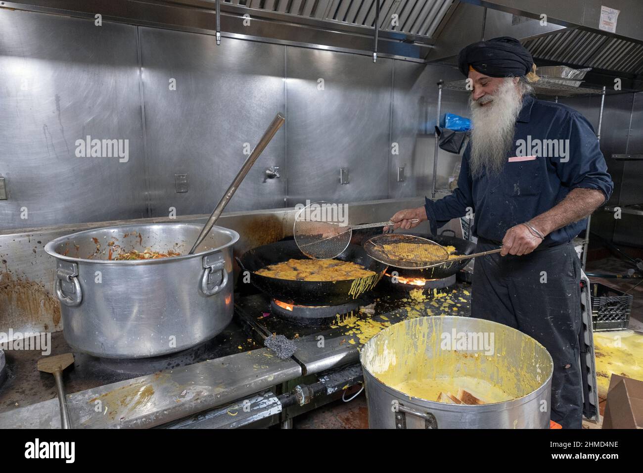 Ein Freiwilliger in einem Sikh-Tempel kocht vegetarisches Essen, das jedem, der darum bittet, zugeführt wird. In South Richmond Hill, Queens, New York City. Stockfoto