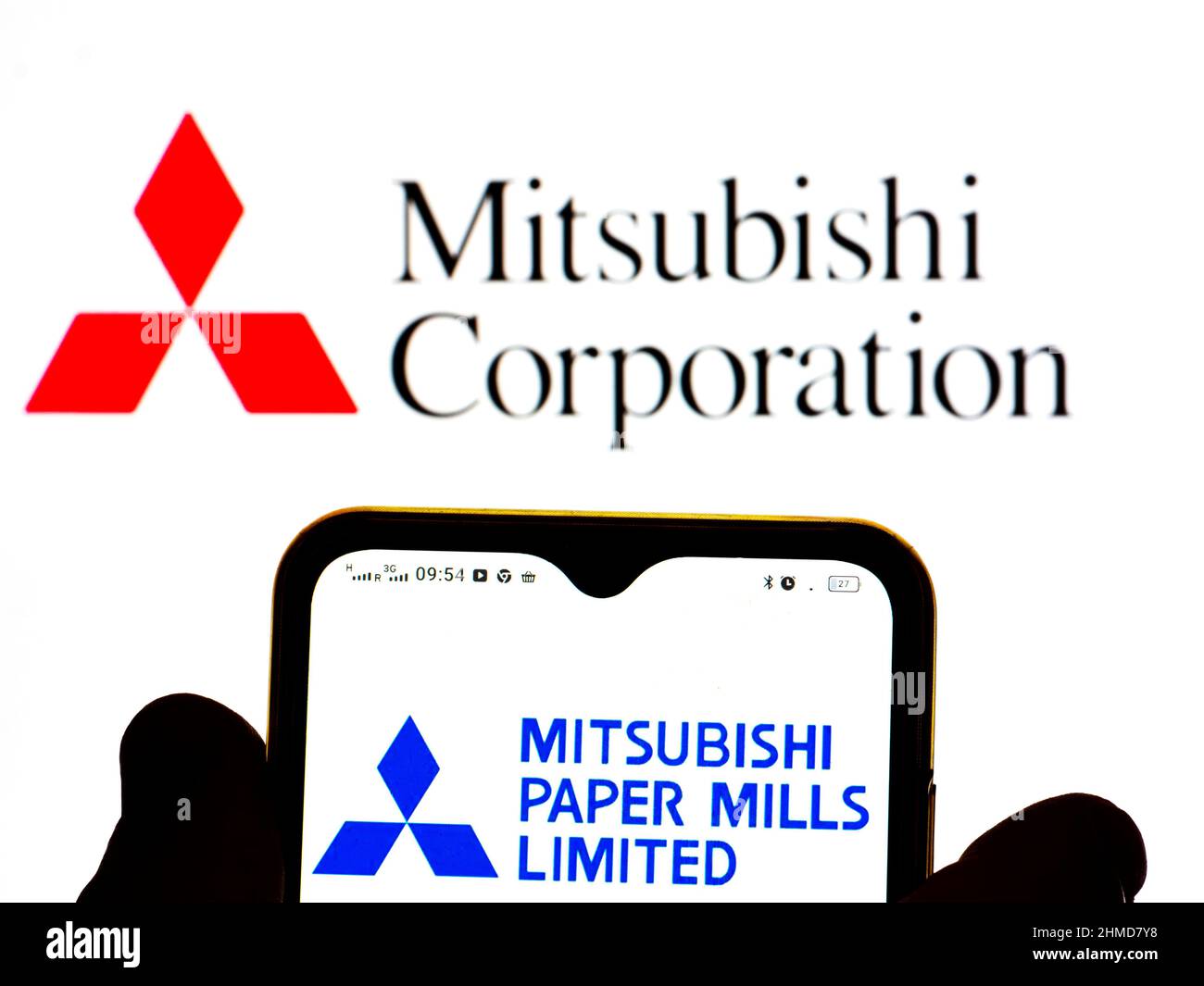 In dieser Abbildung wird das Mitsubishi Paper Mills, Ltd.-Logo auf einem Smartphone-Bildschirm mit einem Mitsubishi Corporation-Logo im Hintergrund angezeigt. Stockfoto