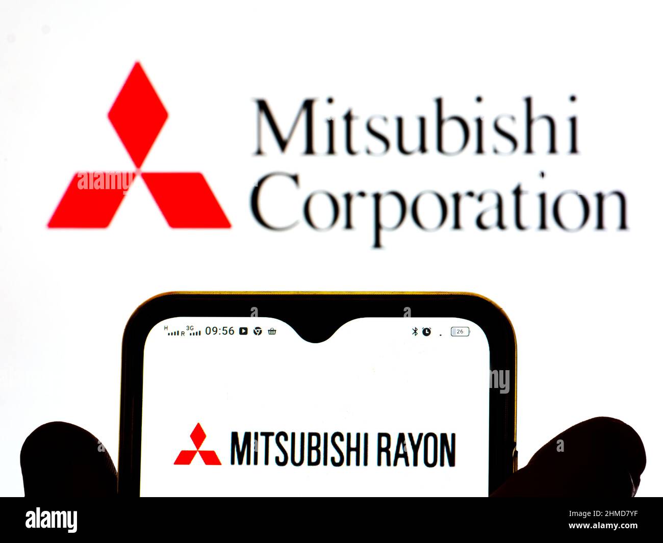 In dieser Abbildung wird das Mitsubishi Rayon Co., Ltd.-Logo auf einem Smartphone-Bildschirm mit einem Mitsubishi Corporation-Logo im Hintergrund angezeigt. Stockfoto