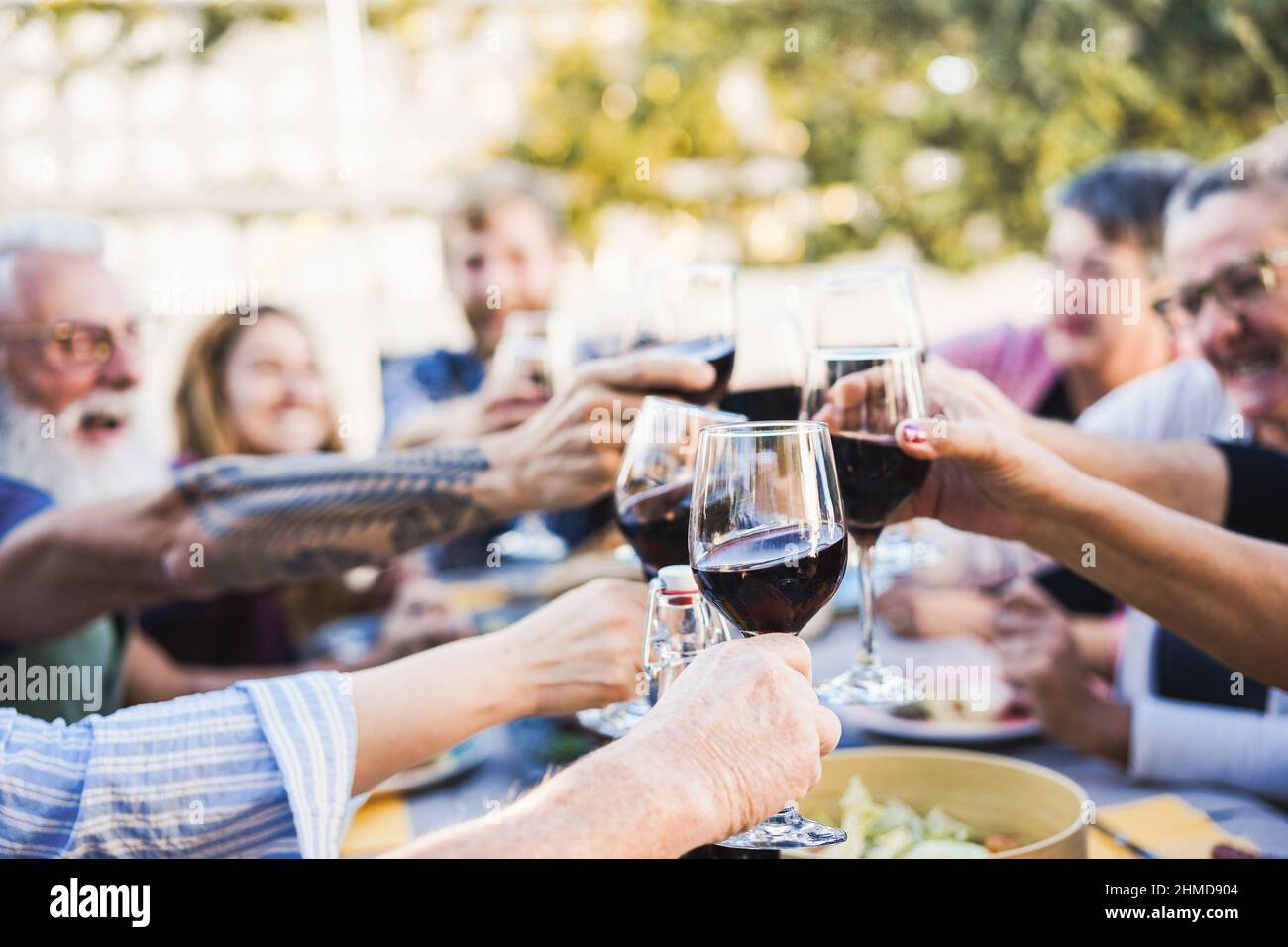 Fröhliche Familie jubelt mit Rotwein beim Barbecue-Dinner im Freien - konzentrieren Sie sich auf die Vorderhand mit Glas Stockfoto