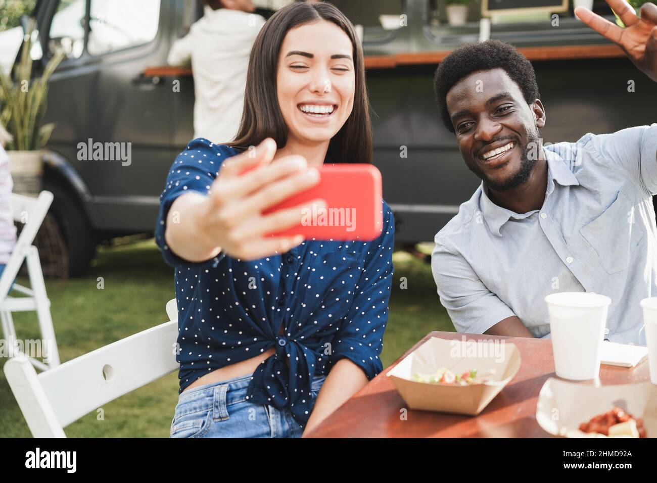 Multirassische Menschen, die Spaß haben, Selfie mit dem Mobiltelefon im Food Truck Restaurant im Freien zu machen - Fokus auf afrikanisches Männergesicht Stockfoto