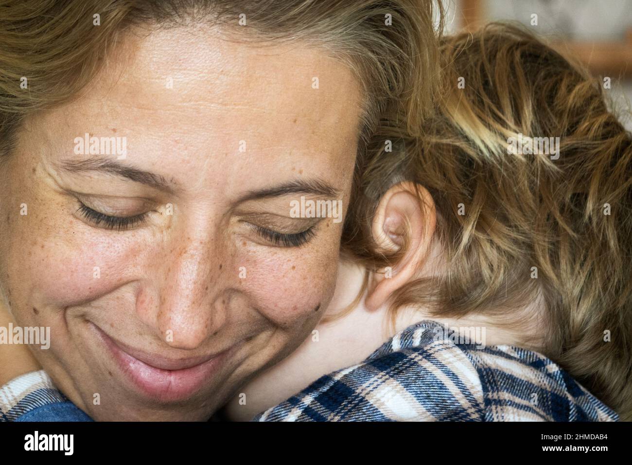 Glückliche schöne Frau umarmt ihren kleinen Sohn zu Hause Stockfoto