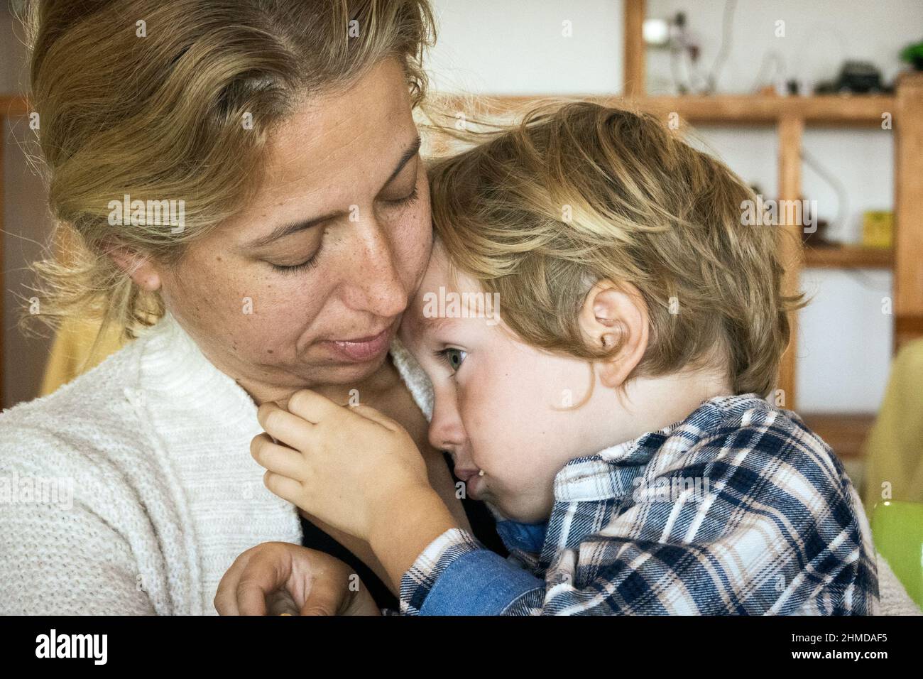 Schöne Frau tröstet ihren kleinen Sohn zu Hause Stockfoto