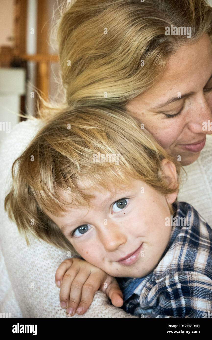 Schöne Frau umarmt ihren lächelnden kleinen Sohn zu Hause Stockfoto