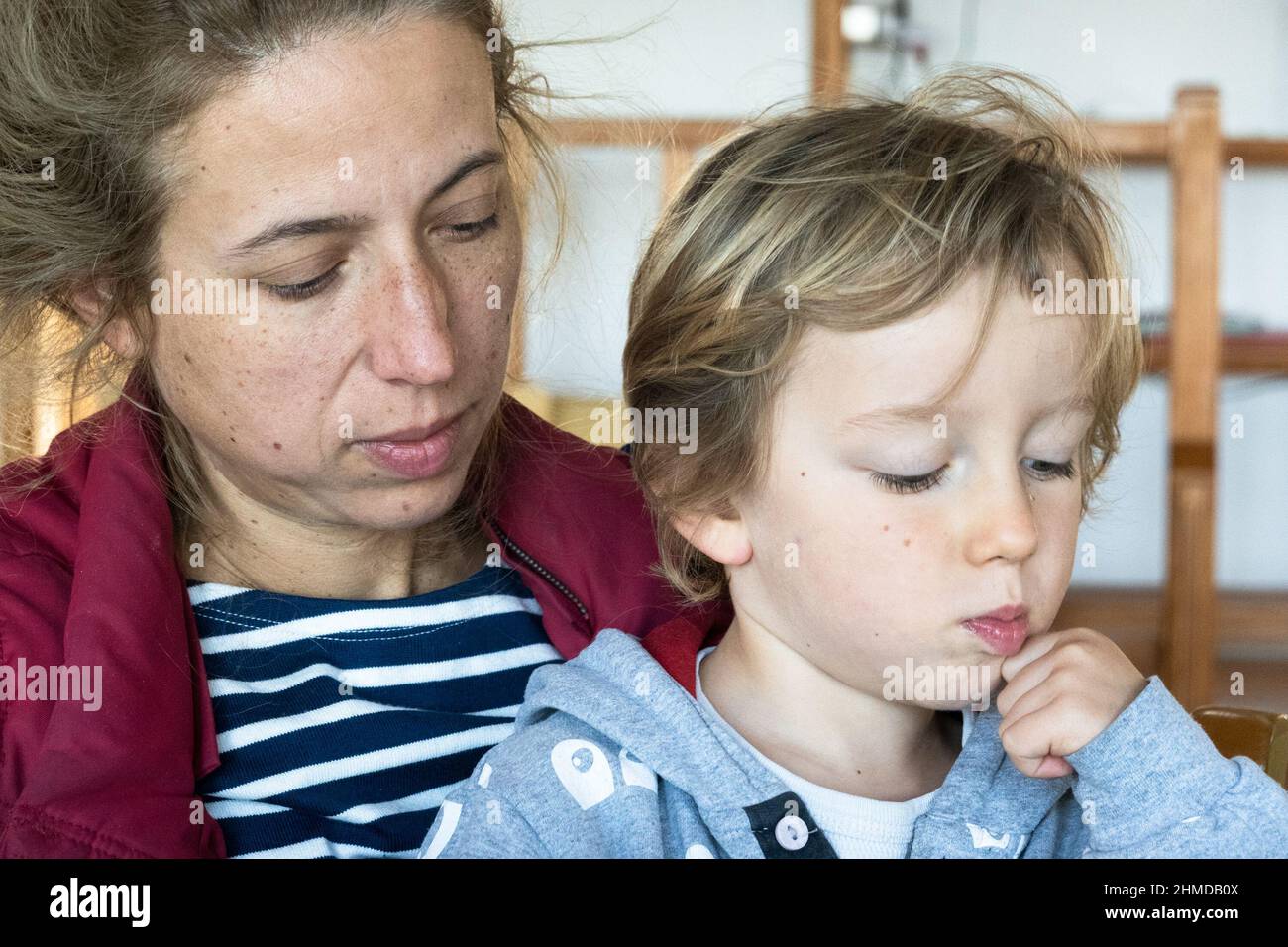 Schöne Frau, die zu Hause mit einem kleinen Sohn sitzt Stockfoto
