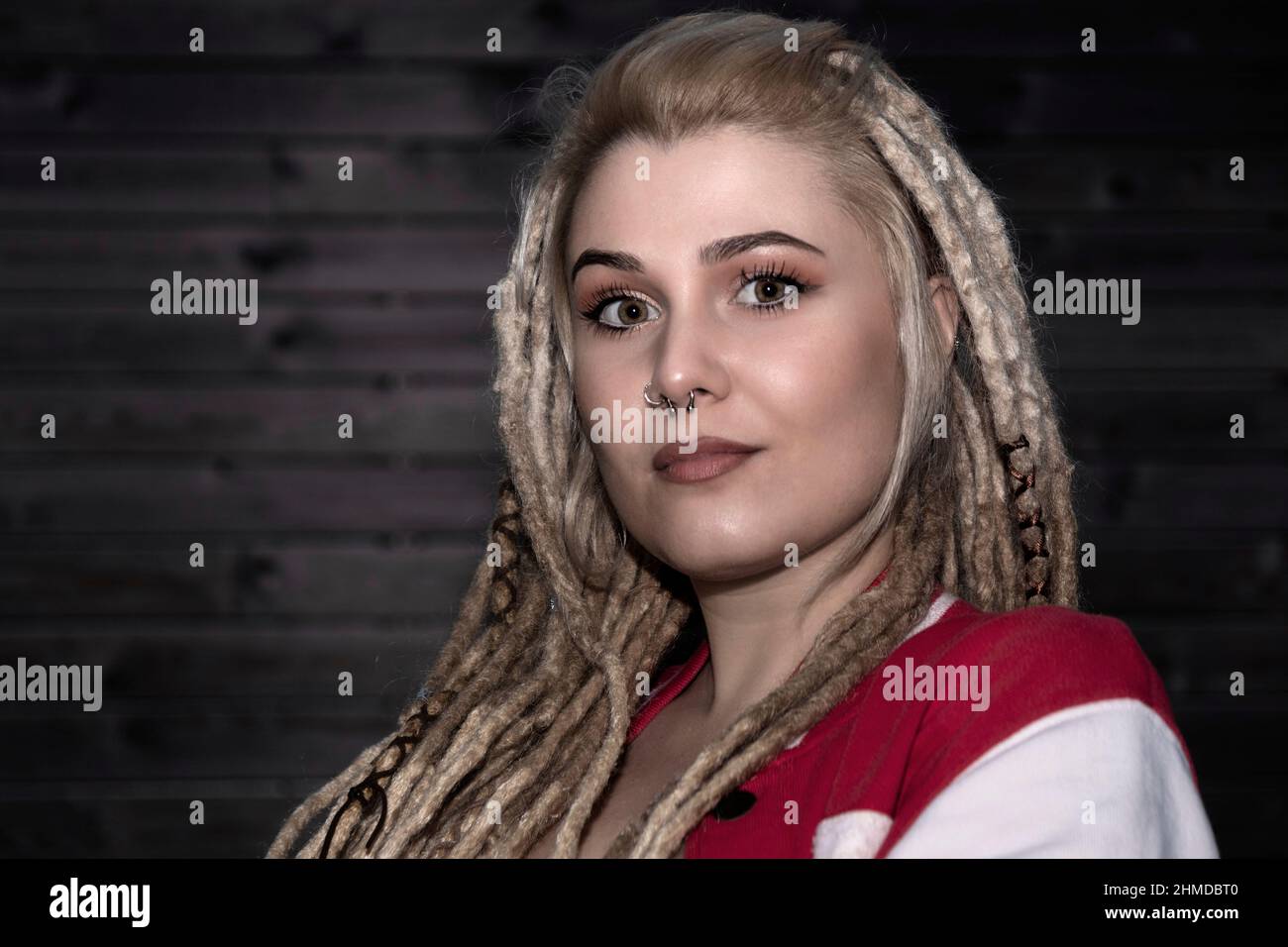 Hübsche blonde Frau mit selbstbewussten Dreadlocks, die die Kamera anschaut Stockfoto