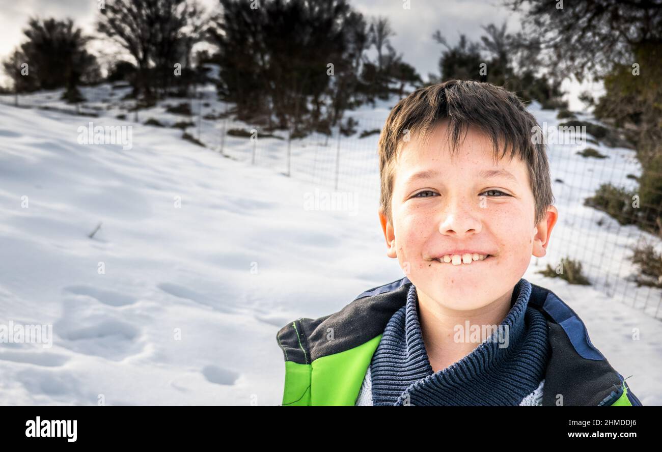 Nahaufnahme eines kleinen Jungen, der auf einem verschneiten Feld Lippe beißt Stockfoto