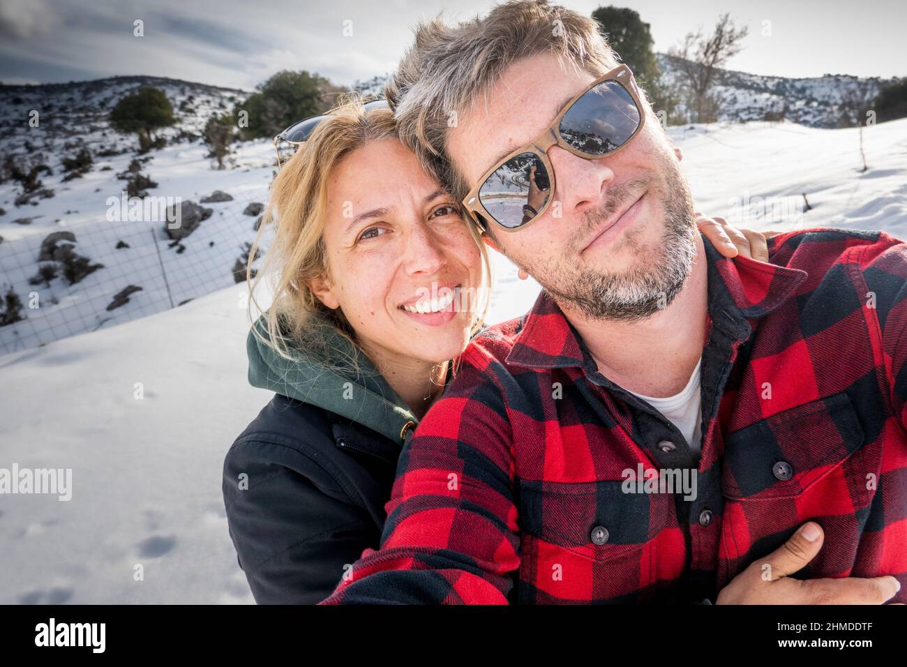 Glückliches Paar, das Selfie auf schneebedeckten Bergen macht Stockfoto