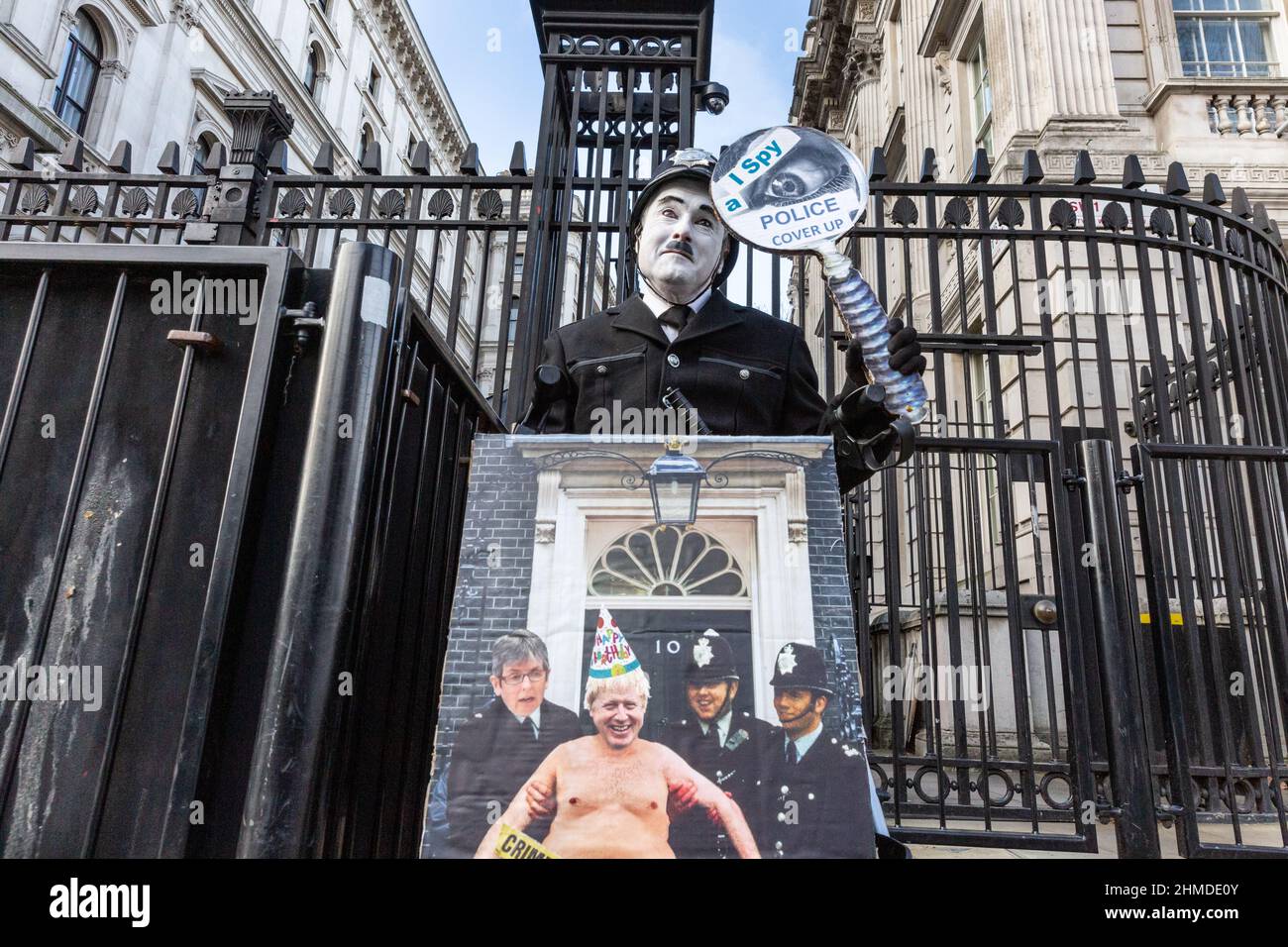 London, Großbritannien. 09th. Februar 2022. Ein Protestler in Charlie Chaplin-Schminke und Polizeiuniform vor der Downing Street hält ein Plakat hoch, das eine „Polizeivertuschung“ beklagt. Kredit: Imageplotter/Alamy Live Nachrichten Stockfoto
