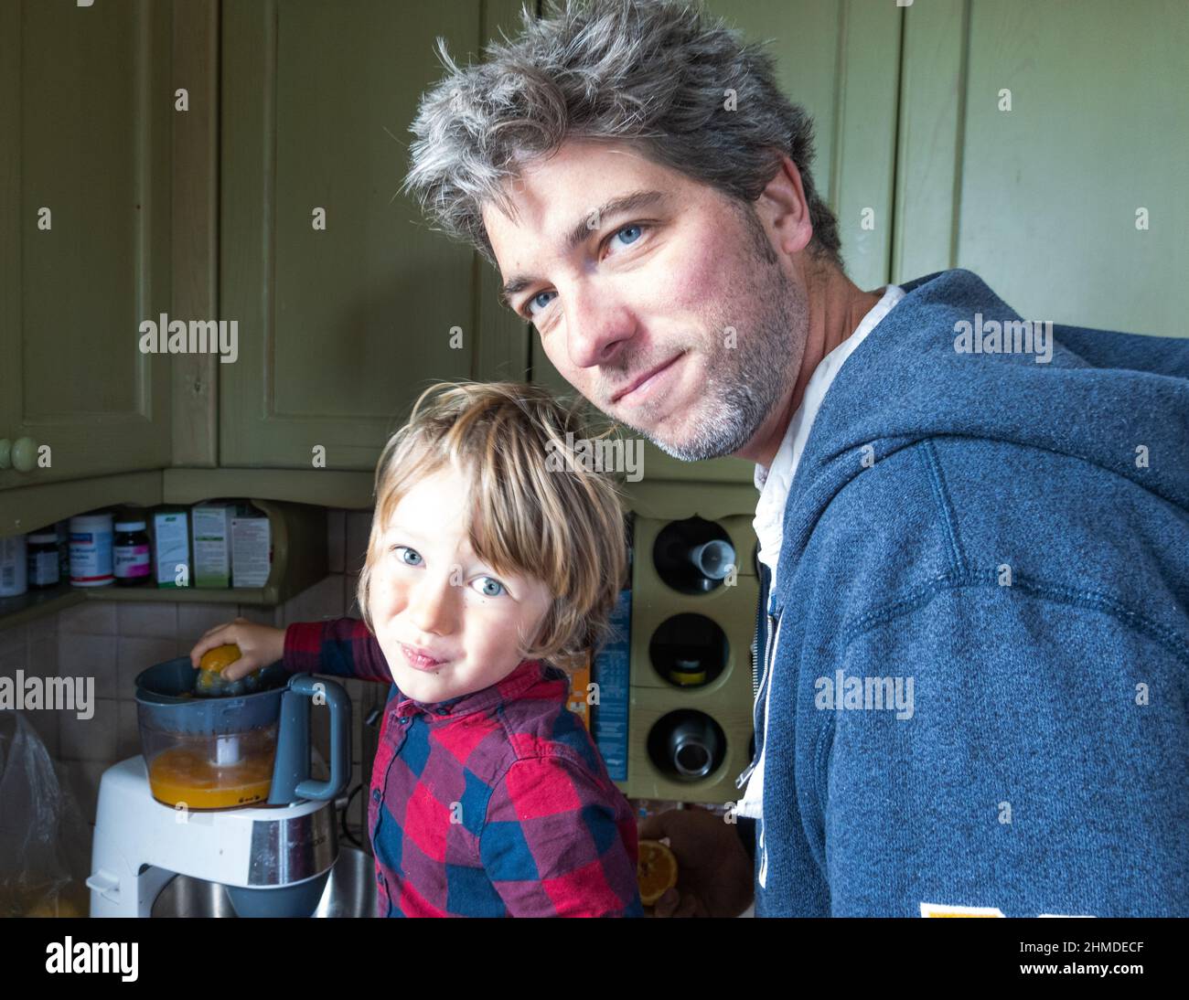 Portrait von Vater und Sohn, der in der Küche frischen Orangensaft zubereitet Stockfoto