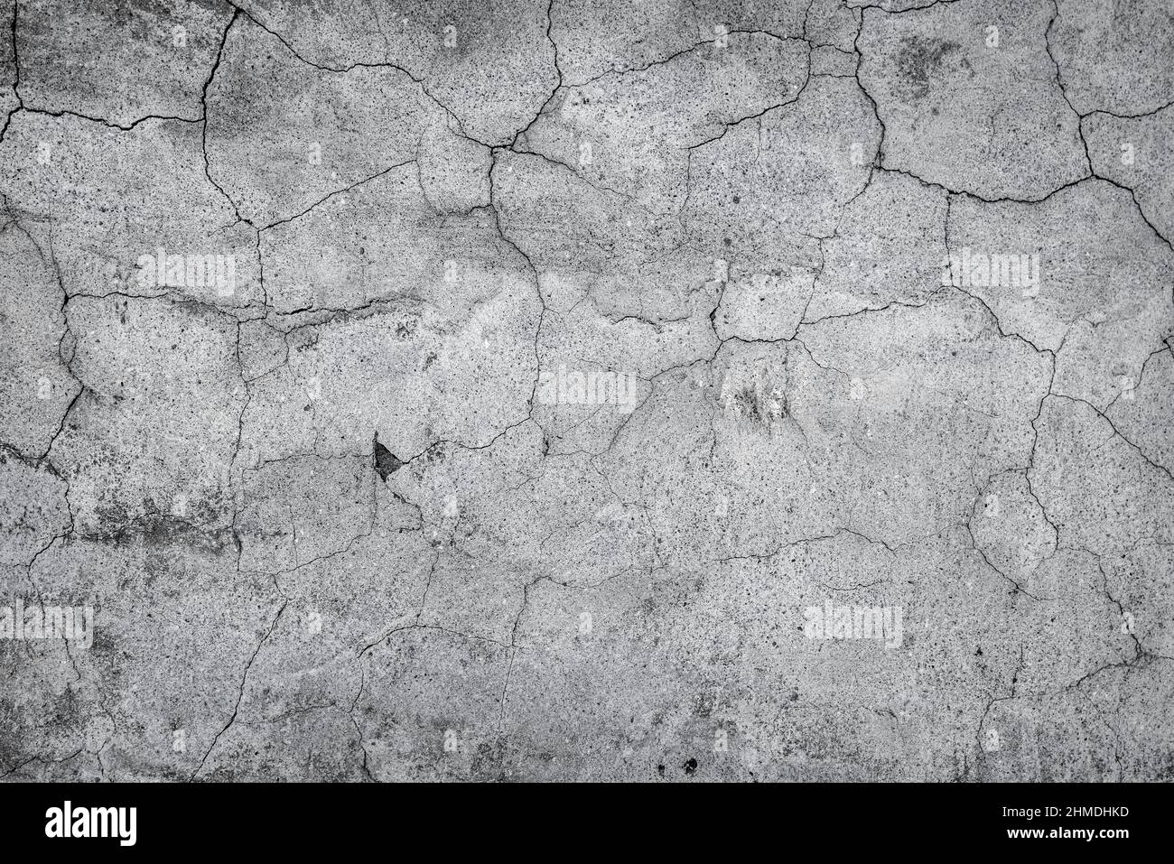 Grau gesprungener Stuck, Beton und Zement Wandmuster. Asymmetrisch und abstrakt gebrochen auf texturiertem Hintergrund. Hochwertige Fotos Stockfoto