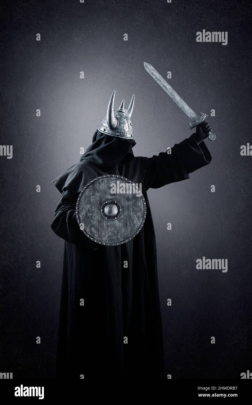 Krieger mit gehörntem Helm, rundem Schild und Schwert im Dunkeln Stockfoto
