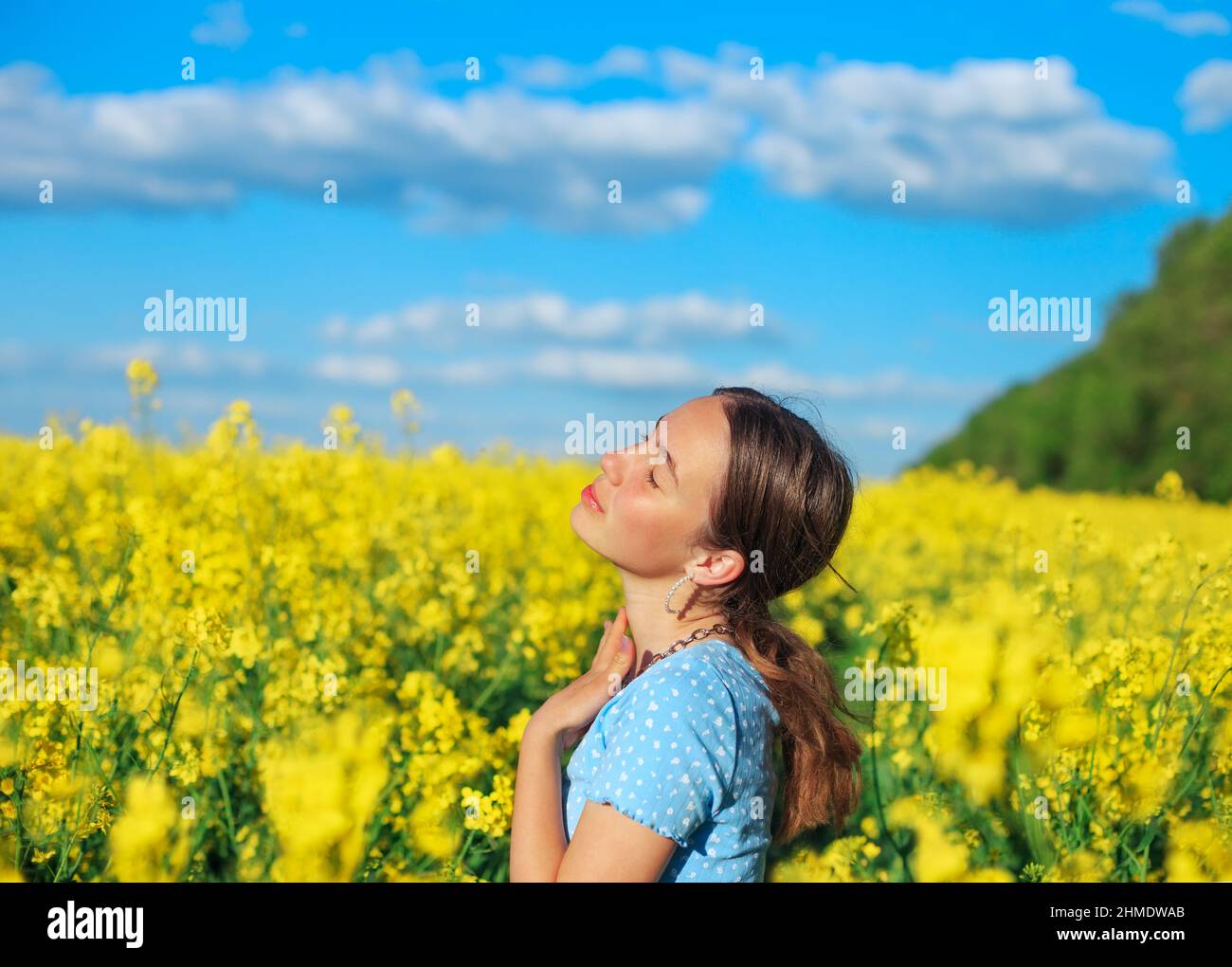 Schöne Teenager-Mädchen lächelt mit gelben Blumen im Sommerfeld Stockfoto