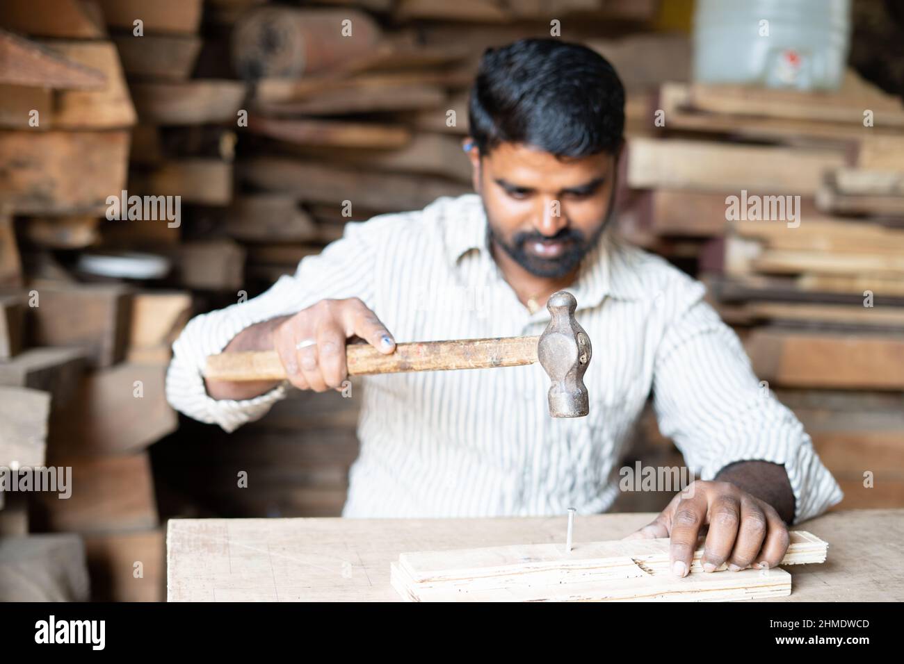 Foucs auf Hammer, junge indische Schreiner beschäftigt schlagen Nägel mit Hammer zu Holz in der Werkstatt - Konzept der Handwerker, blauen Kragen Arbeit und qualifizierte Handarbeit Stockfoto