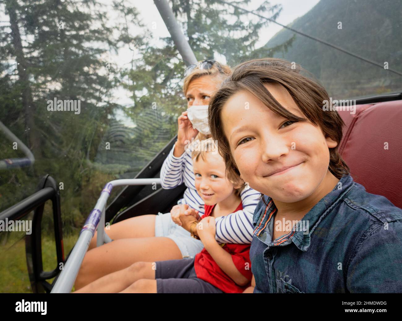 Glücklicher Junge, der mit Mutter und Bruder auf der Fahrt mit der Seilbahn in Österreich Selife macht Stockfoto