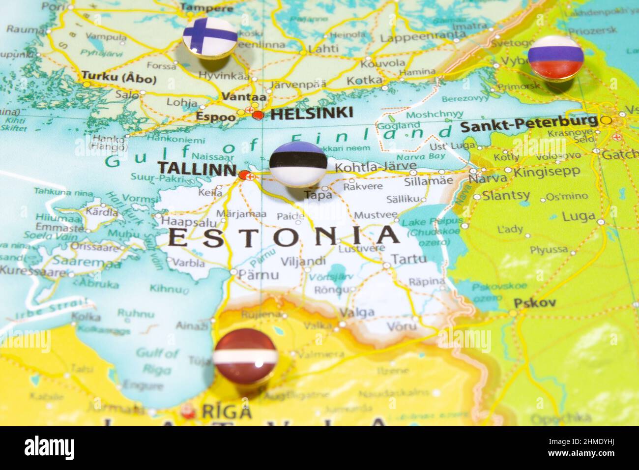 Estnische Nationalflagge auf der Europakarte. Makro Nahaufnahme des Landes Estland auf einer bunten und verschwommenen Weltkarte mit Fokus auf das Kapital Stockfoto