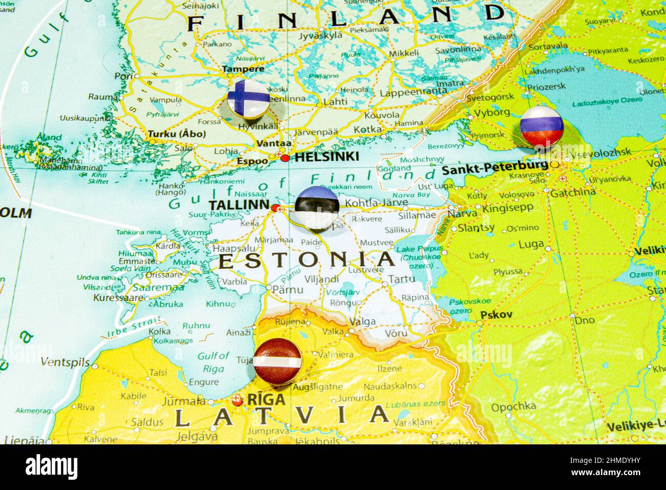 Estnische Nationalflagge auf der Europakarte. Makro Nahaufnahme des Landes Estland auf einer bunten und verschwommenen Weltkarte mit Fokus auf das Kapital Stockfoto