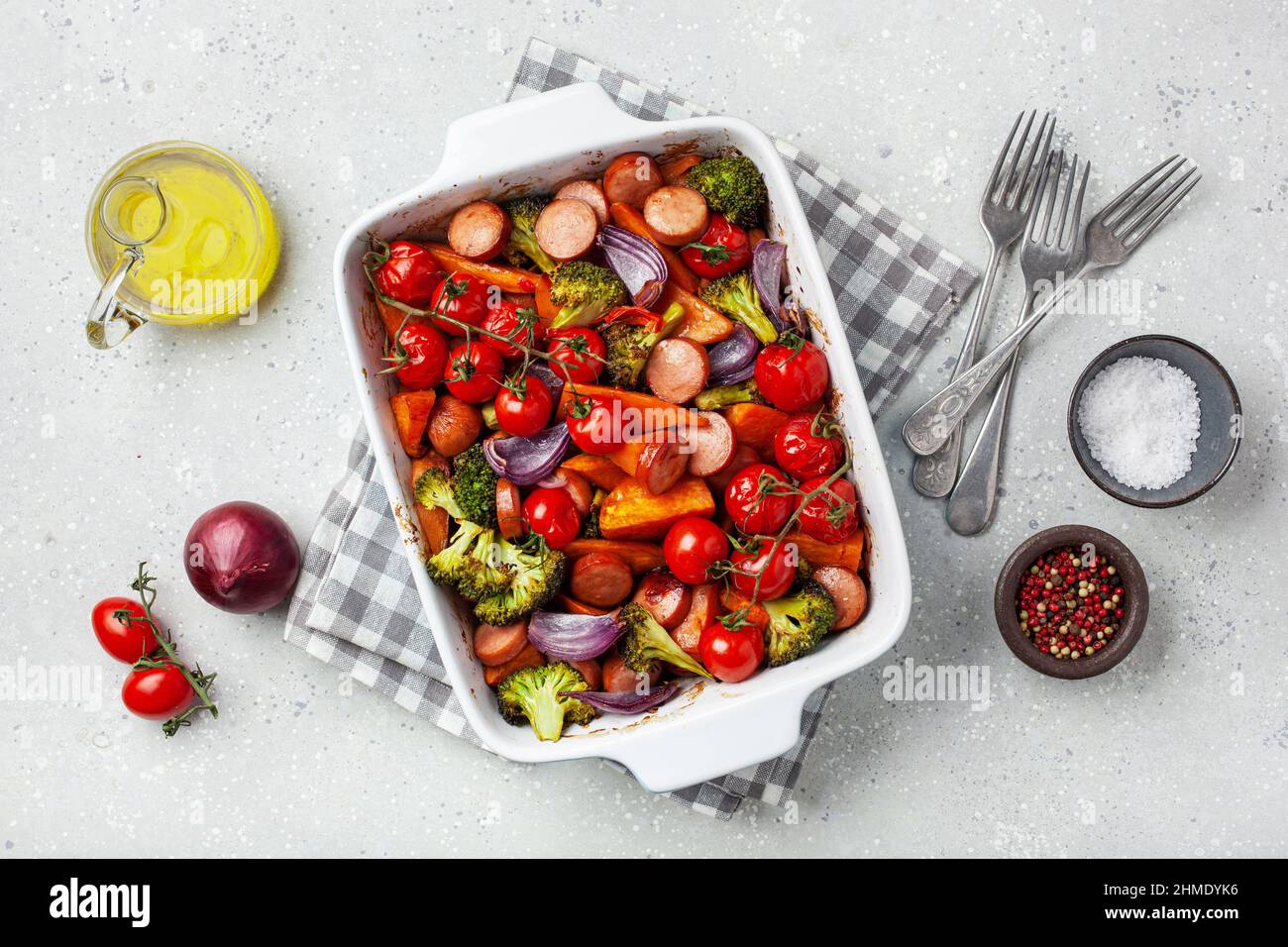 Im Ofen gebackenes Gemüse und Würstchen, gesundes Mittagessen, Süßkartoffel Zwiebel Tomate Brokkoli Stockfoto