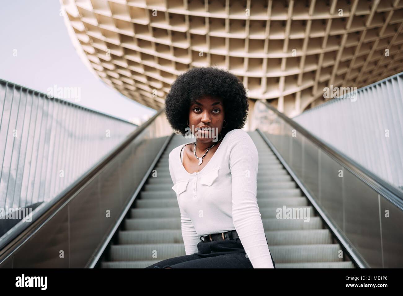 Modetrportrait einer jungen schwarzen Frau, die auf einer Rolltreppe auf der Straße sitzt Stockfoto