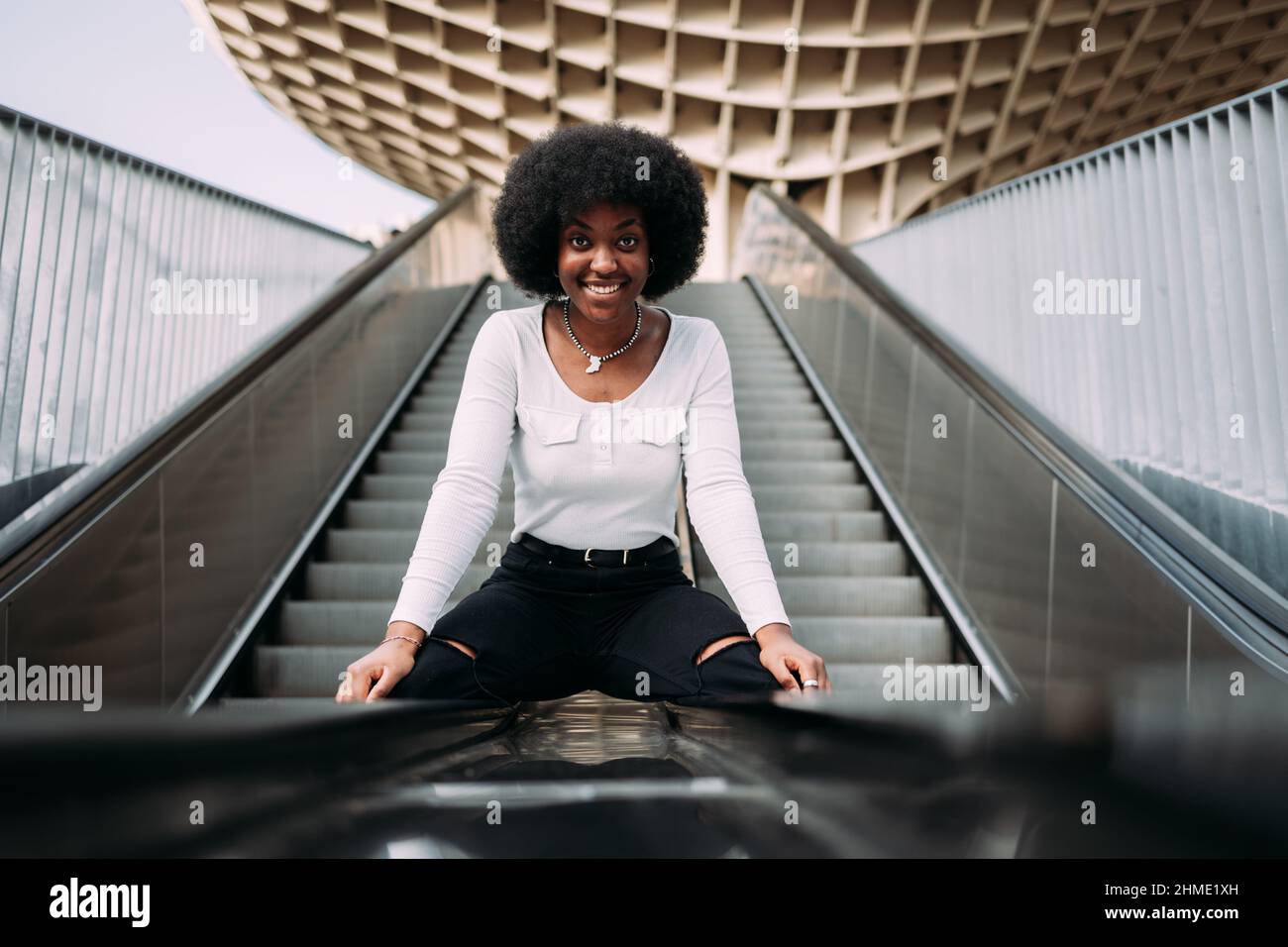 Schöne schwarze Teenager-Mädchen ritzen eine Rolltreppe Geländer Blick auf Kamera Stockfoto