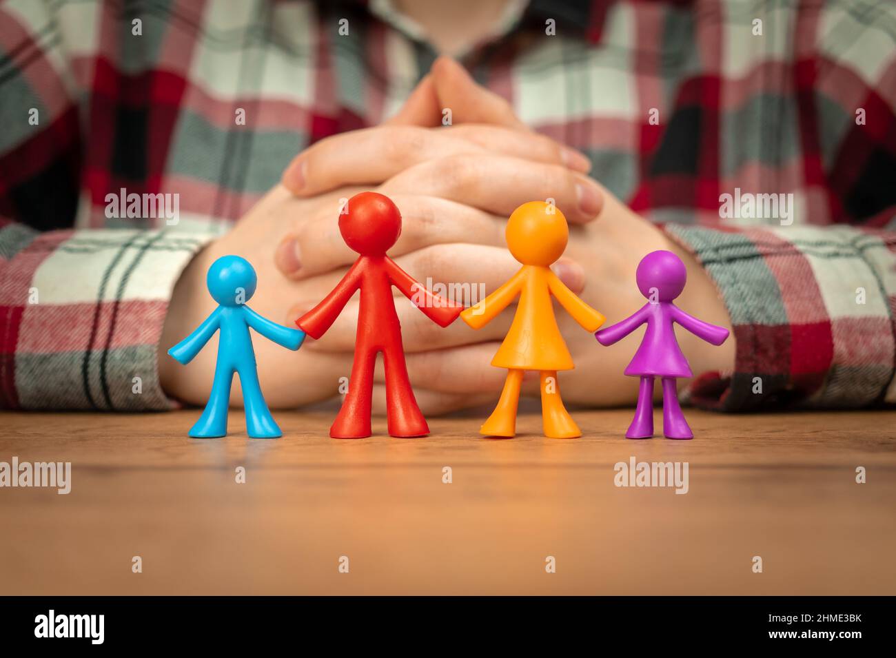 Familienversicherungskonzept mit bunten Familienfiguren auf Holztisch Stockfoto