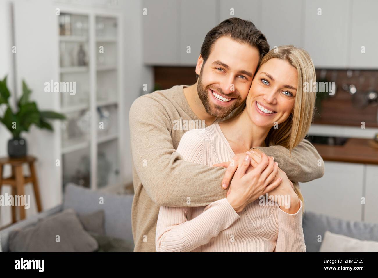 Harmonische Beziehungen. Glückliches Ehepaar posiert für ein Foto in der Küche. Der kaukasische Ehemann umarmte seine Frau von hinten. Glücklichste Herzen machen das glücklichste Zuhause Konzept Stockfoto