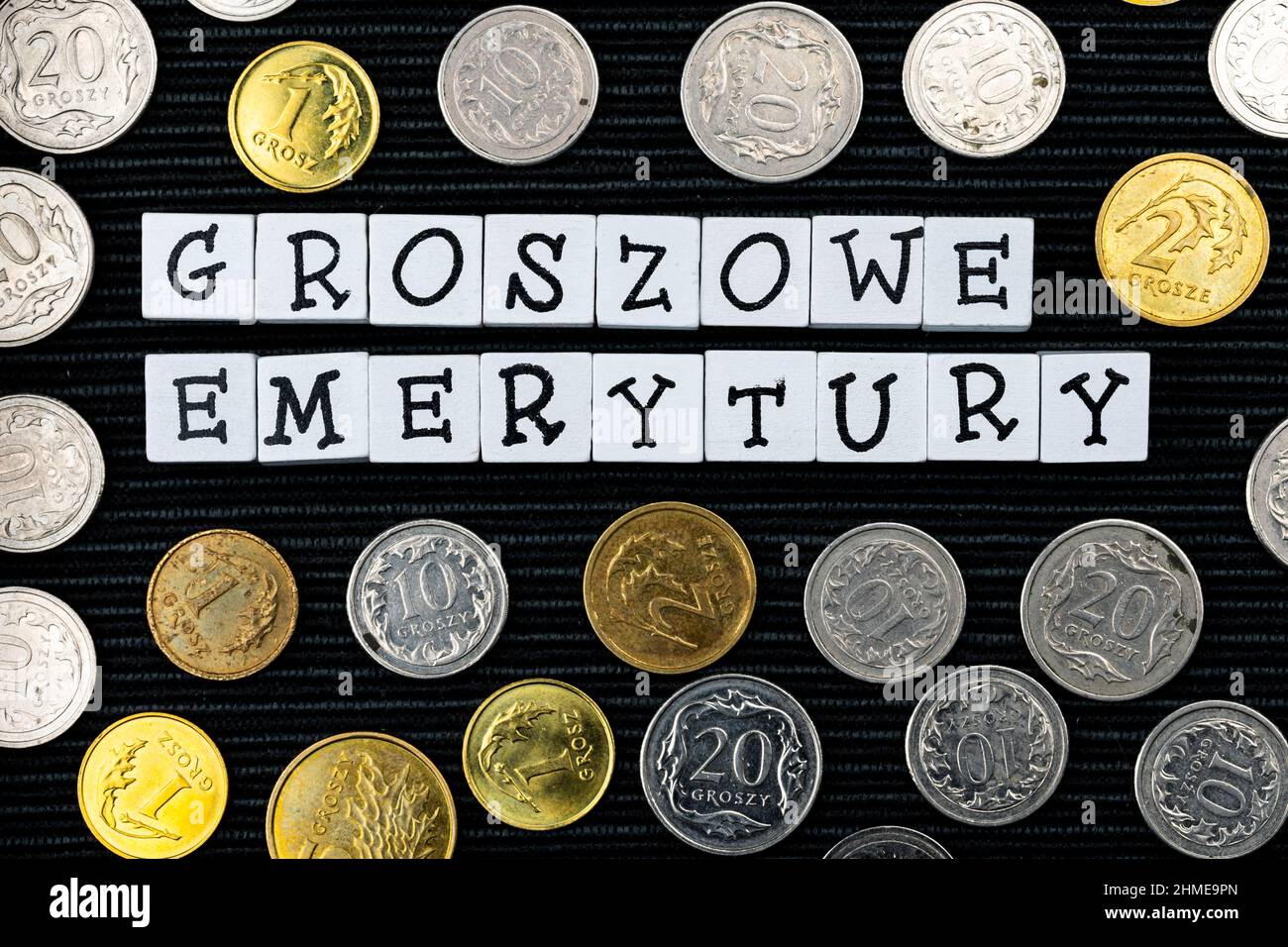 Die Formulierung "groszowe Emerytury" wurde übersetzt mit "Penny Renten" und vielen polnischen Münzen auf schwarzem Hintergrund. Neue Steuervorschriften in Polen. Foto-Tak Stockfoto