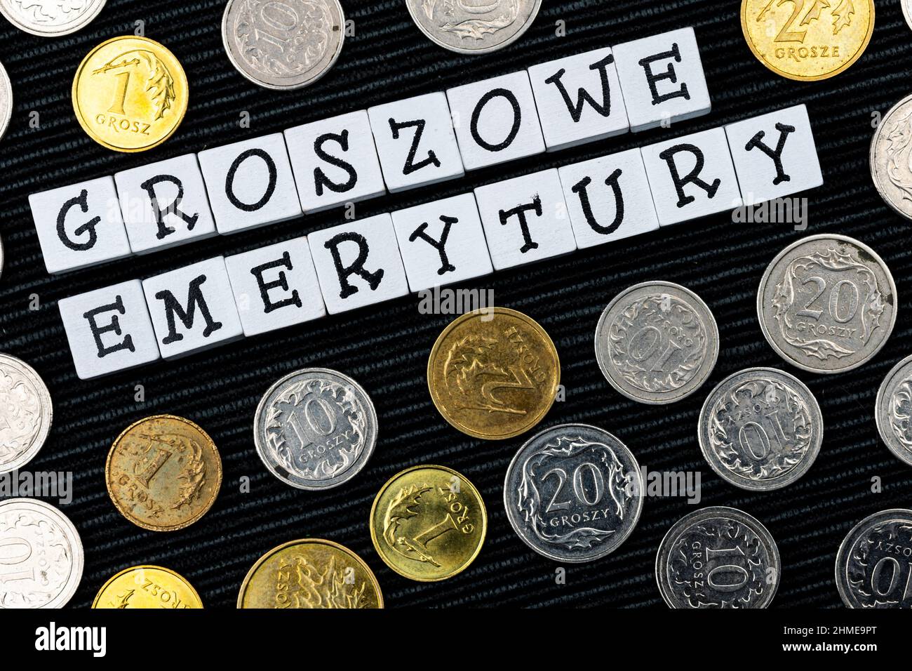 Die Formulierung "groszowe Emerytury" wurde übersetzt mit "Penny Renten" und vielen polnischen Münzen auf schwarzem Hintergrund. Neue Steuervorschriften in Polen. Foto-Tak Stockfoto
