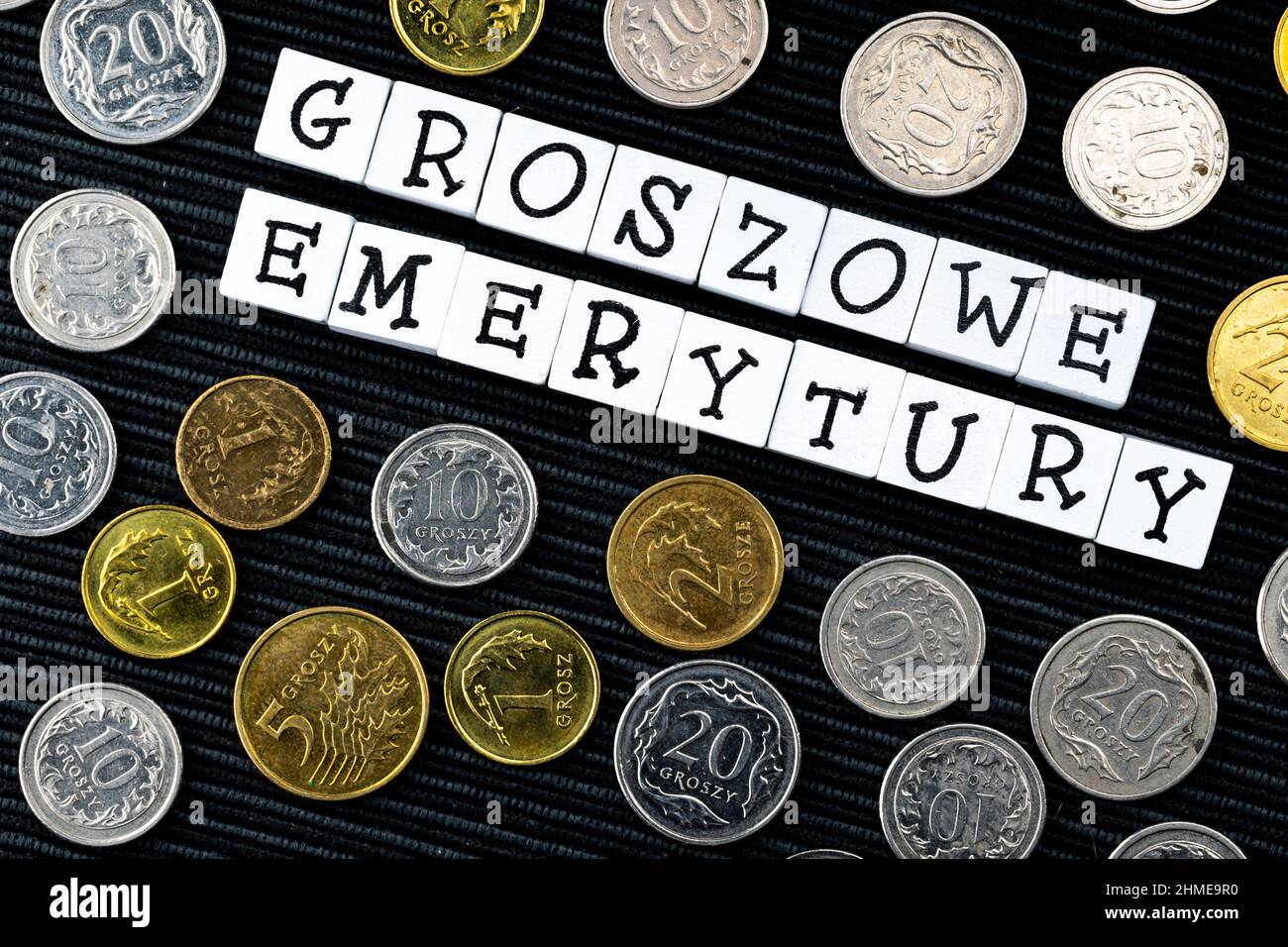 Die Formulierung "groszowe Emerytury" wurde übersetzt mit "Penny Renten" und vielen polnischen Münzen auf schwarzem Hintergrund. Neue Steuervorschriften in Polen. Foto-Tak Stockfoto
