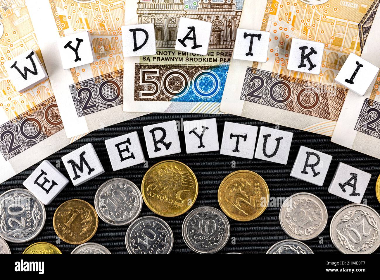 Die Formulierung "wydatki emerytury" wurde übersetzt mit "Spesenrenten" und vielen polnischen Münzen und Banknoten auf schwarzem Hintergrund. Neue Steuervorschriften in P Stockfoto
