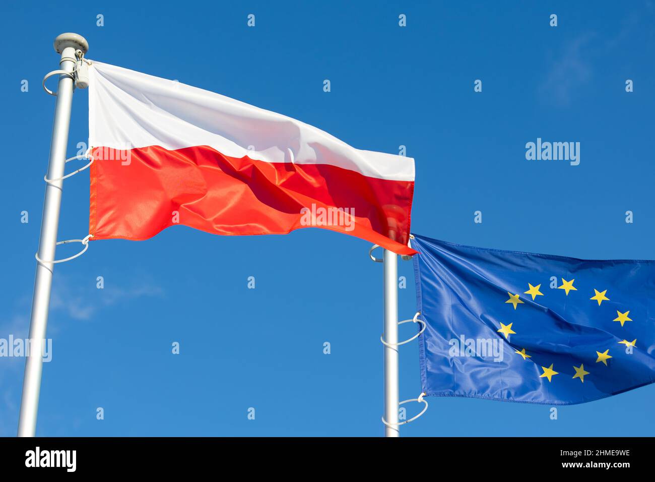 Die Flaggen Polens und der Europäischen Union winken gegen den blauen Himmel Stockfoto